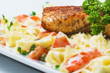Salmon Fettucine Pasta Fresh salmon over fresh fettuccine noodles, capers, and tomatoes in our homemade Alfredo sauce.