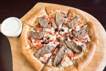 Greek Special Pizza Onions, tomatoes, Greek feta, Greek olives, and mozzarella. Topped with Greek gyro meat, and served with a side of homemade Tzatziki sauce.