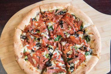 Lachlan & Leo's Favorite Pizza Pizza sauce base, mushrooms, green peppers, onions, black olives, fresh garlic, diced tomatoes, spinach, sunflower seeds, feta, and mozzarella cheese with shredded pepperoni on top.