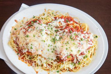 Baked Chicken Parmesan "The most bang for your buck - our largest dish” breaded chicken breast, spaghetti, marinara, parmesan, and mozzarella.