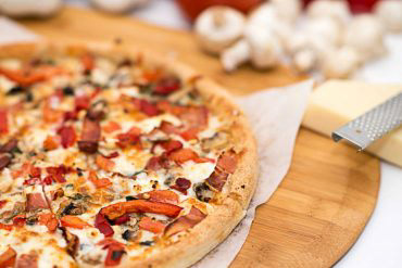 Pizza al Proscuitto Olive oil glaze with mushrooms, prosciutto ham, tomatoes, goat cheese, roasted peppers, fresh basil, and mozzarella.
