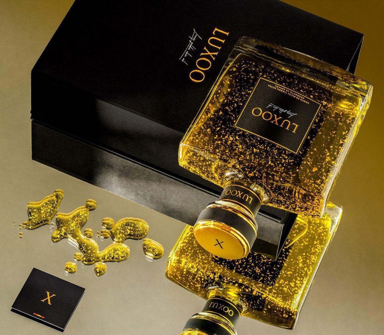 Botella vertiendo AOVE con oro 24K y tarjeta X. Lifestyle.