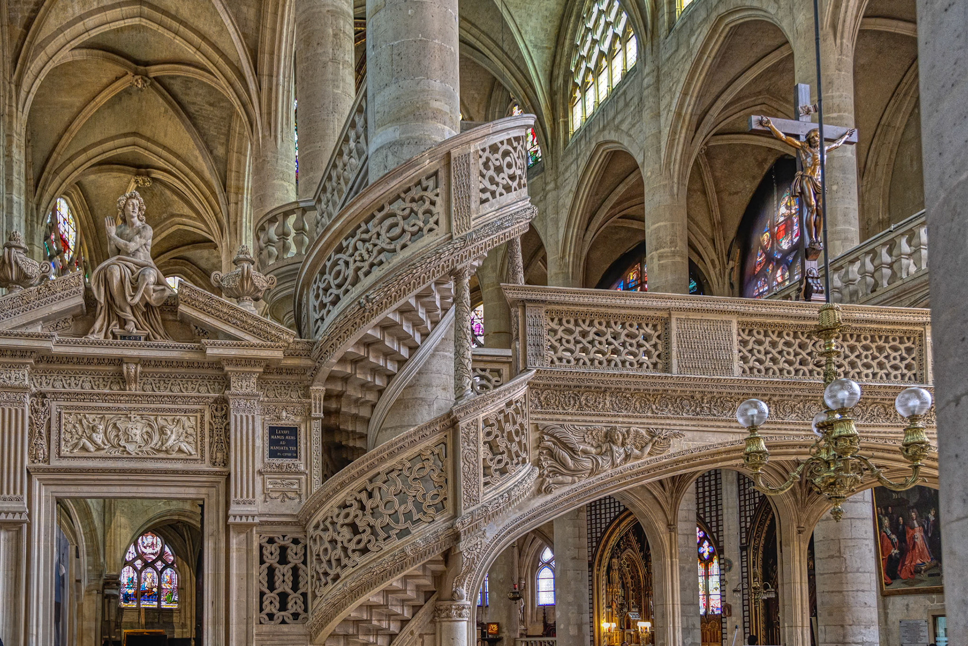 Christ on the cross, framed by the intricate architecture and vivid stained-glass narrative.