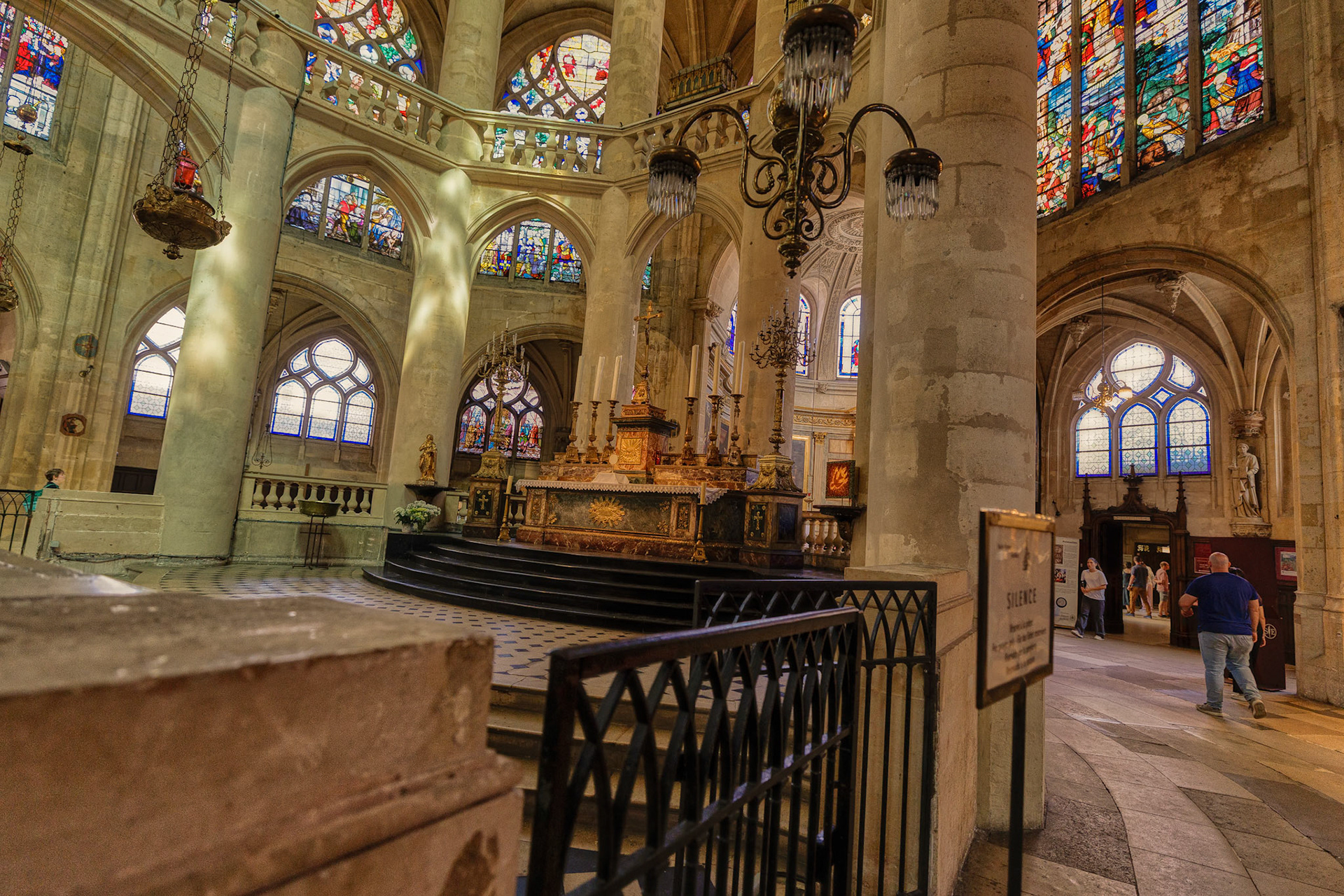 A side aisle filled with golden warmth, framed by vibrant frescoes and arches.
