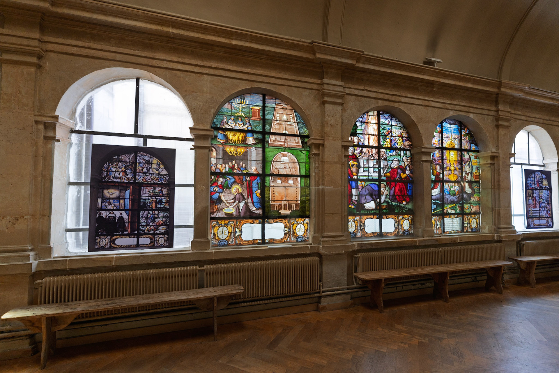 Sunlight filters through five centuries of colored glass, illuminating the cloister passage.