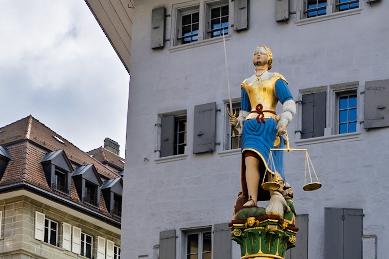 The statue atop the fountain is a symbolic portrayal of Lady Justice:Blindfolded, for impartialityHolding a sword in her right hand, symbolizing authorityHolding a balance scale in her left, symbolizing fairnessWith one knee exposed, symbolizing mercy.. Figures representing the Pope, Emperor, Grand Turk, and a magistrate are tucked under her robes, signifying their subjugation to justice