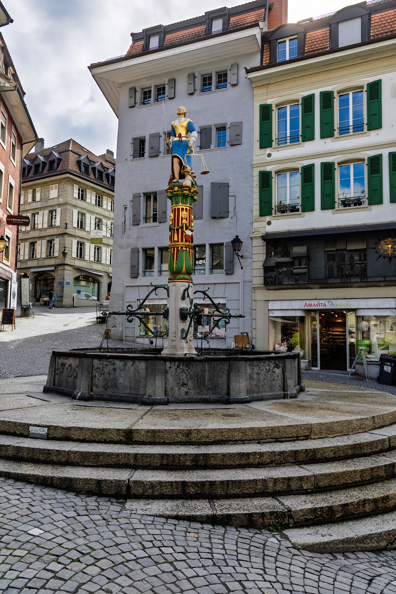 The statue atop the fountain is a symbolic portrayal of Lady Justice:Blindfolded, for impartialityHolding a sword in her right hand, symbolizing authorityHolding a balance scale in her left, symbolizing fairnessWith one knee exposed, symbolizing mercy.. Figures representing the Pope, Emperor, Grand Turk, and a magistrate are tucked under her robes, signifying their subjugation to justice.