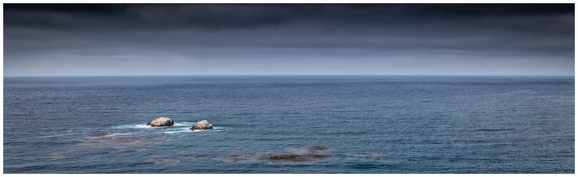 Off the coast of California near Carmel this two rock islands provide a simple scene in the vast blue of the Pacific Ocean.