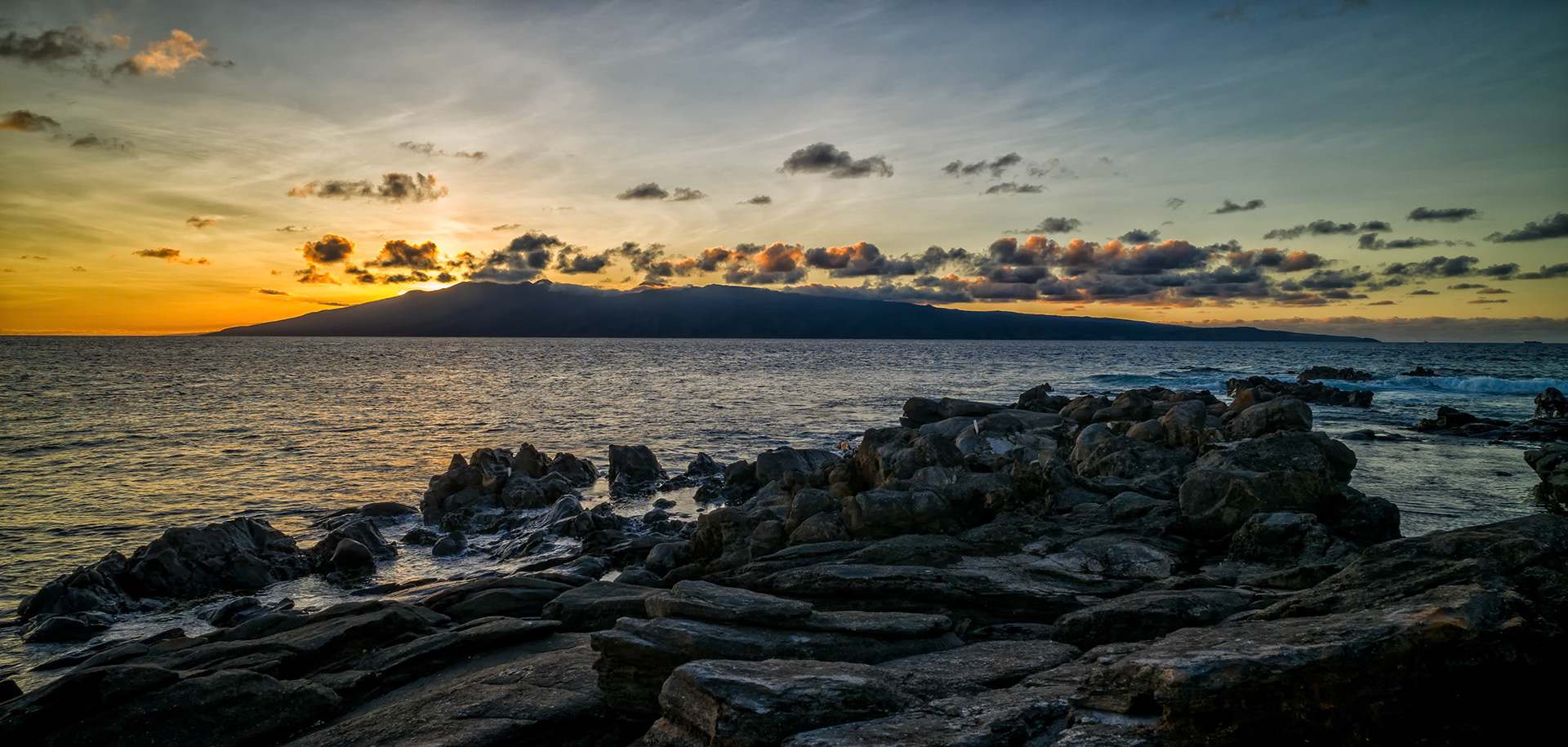 The island of Moloka'i as the backdrop for a sunset off the coast of Maui.