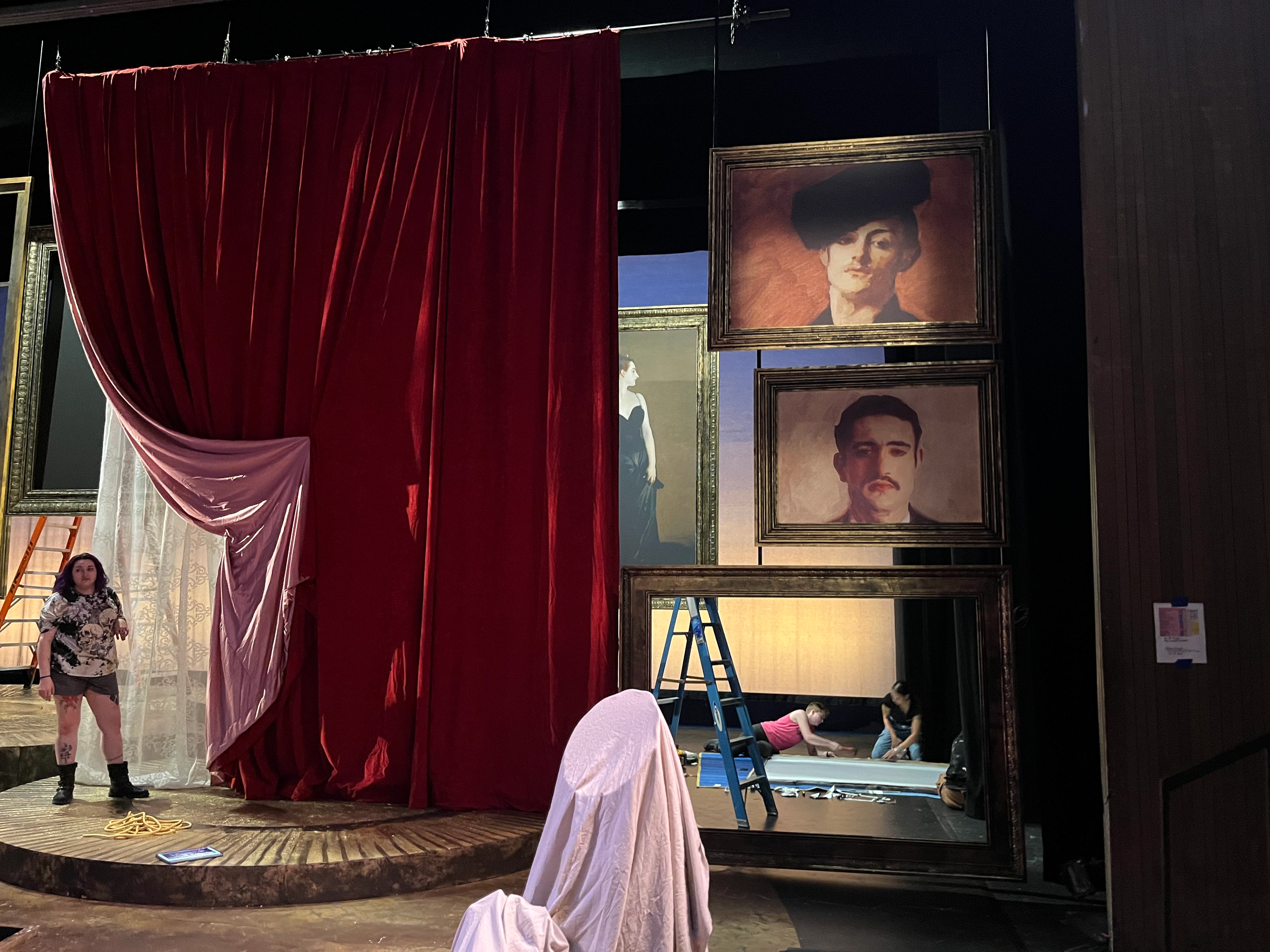 Staff works on installing one of the tracking portraits while TD Natalie Hining discusses curtain swag with the designer.