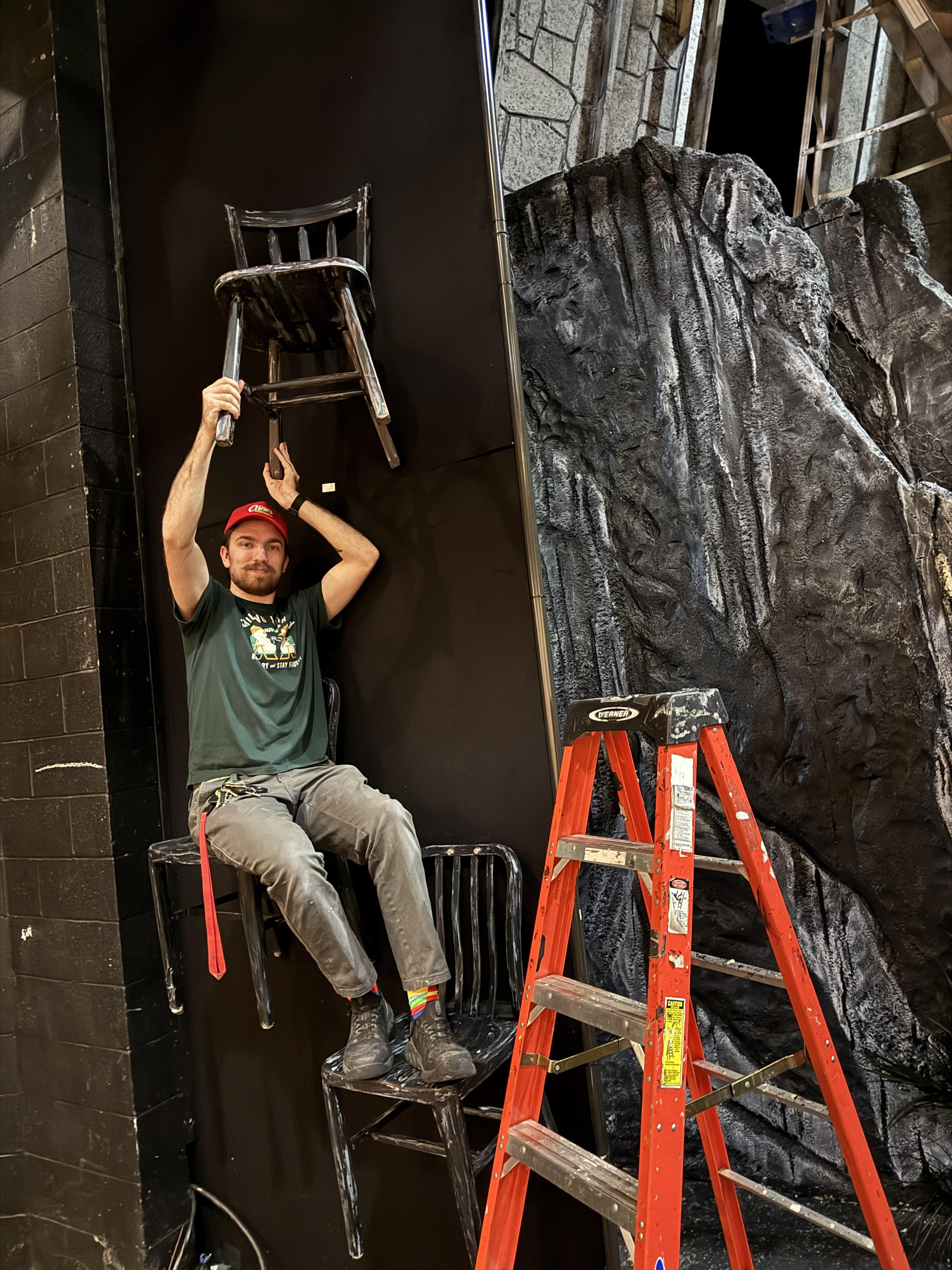 Shop supervisor Bruce helping hang decorative chairs while demonstrating the sittable chairs
