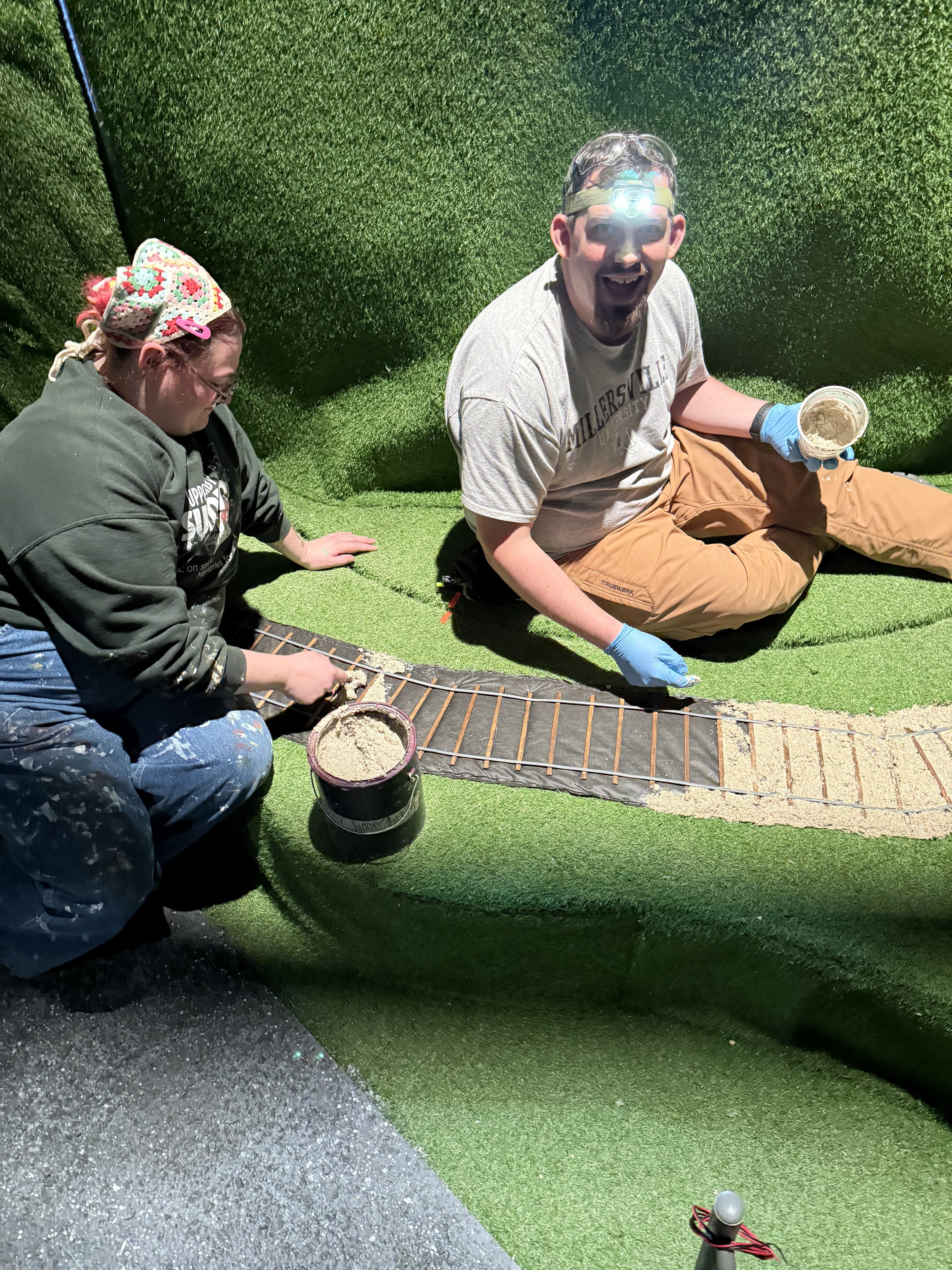 Scenic charge Diane & carpenter Josh filling train tracks with sediment!