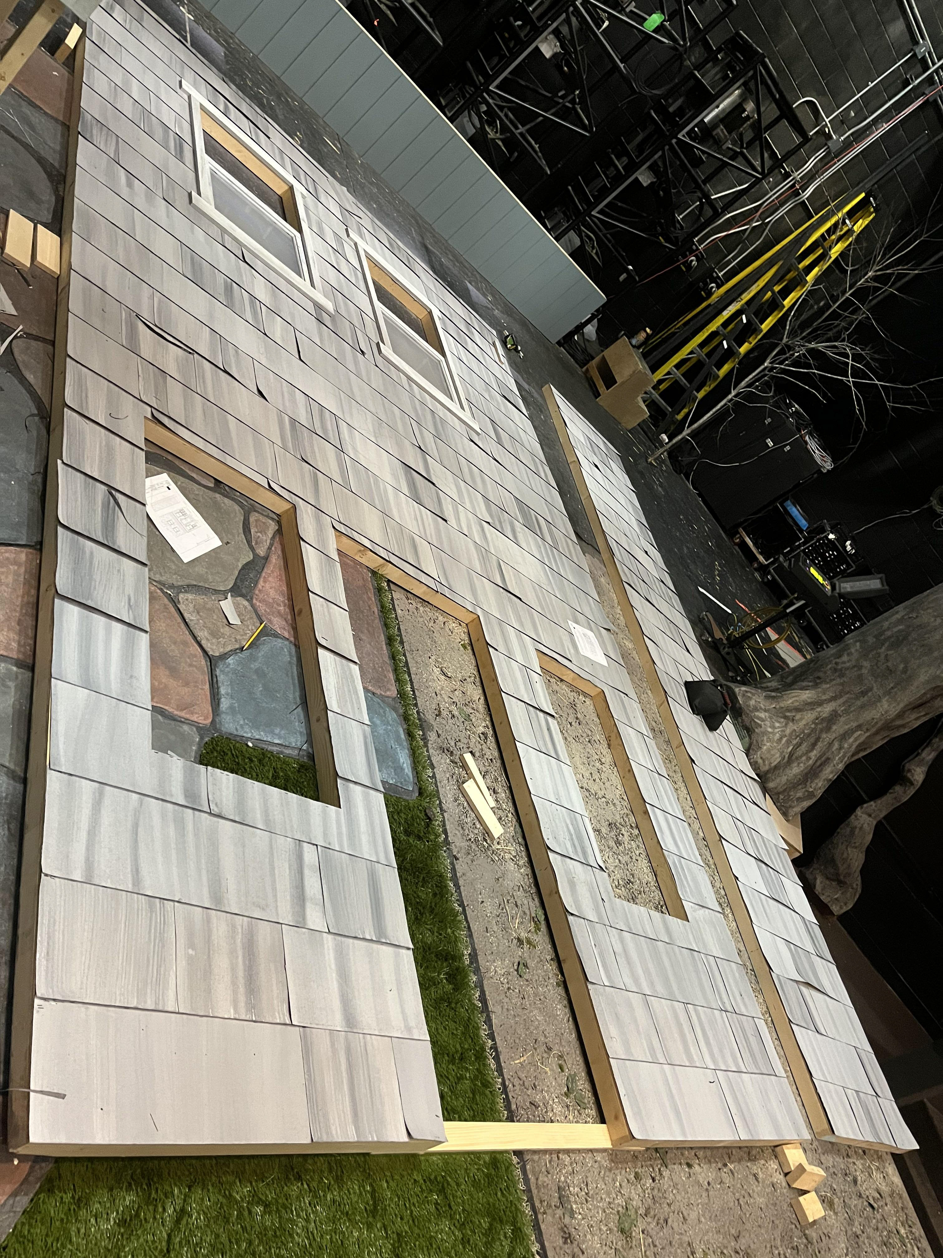Individually attached shingles to stage left house to achieve aging look.