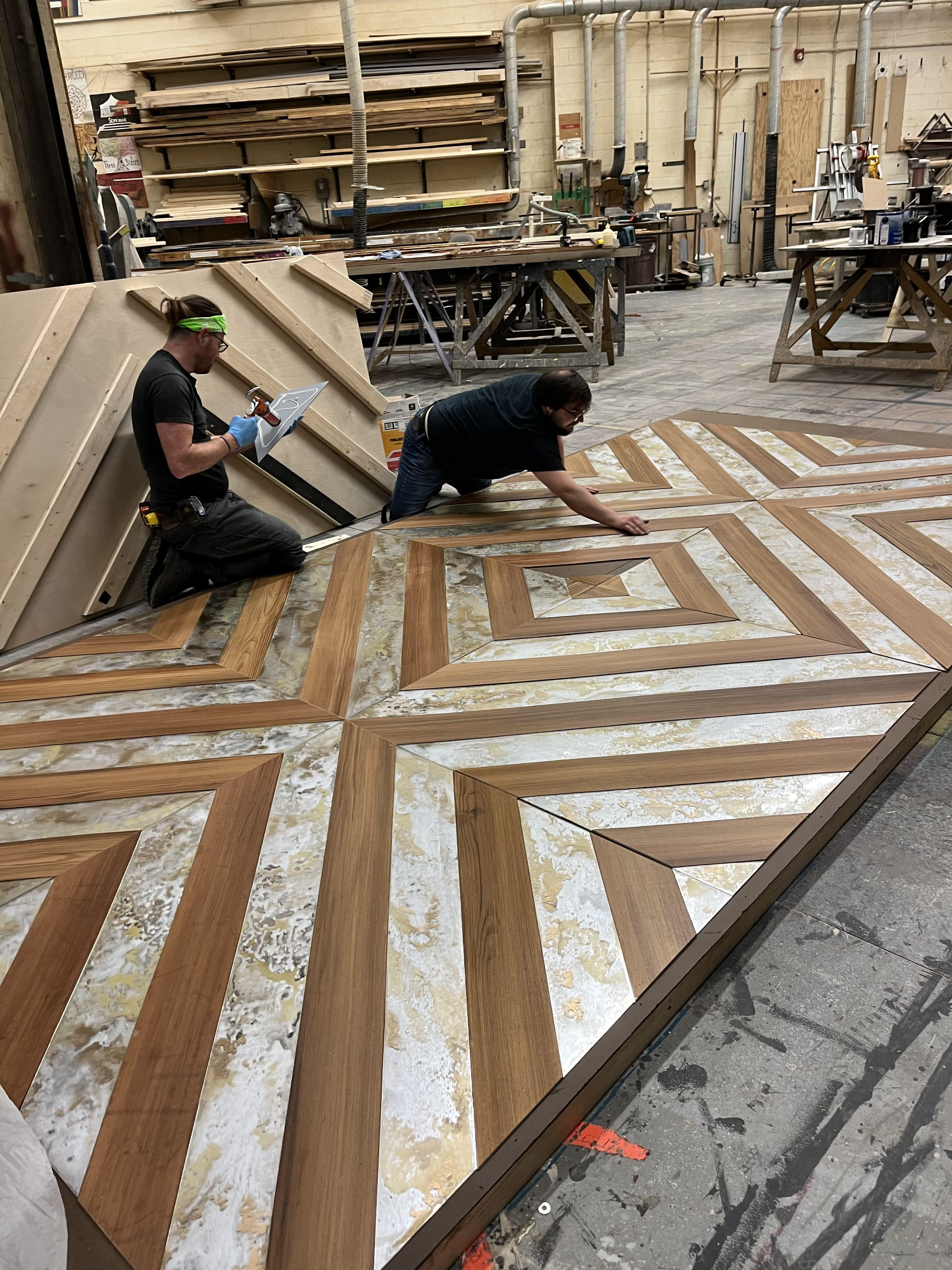 2x4's were screwed on plywood in the chevron pattern to weight down mirror panels evenly while liquid nails cured.