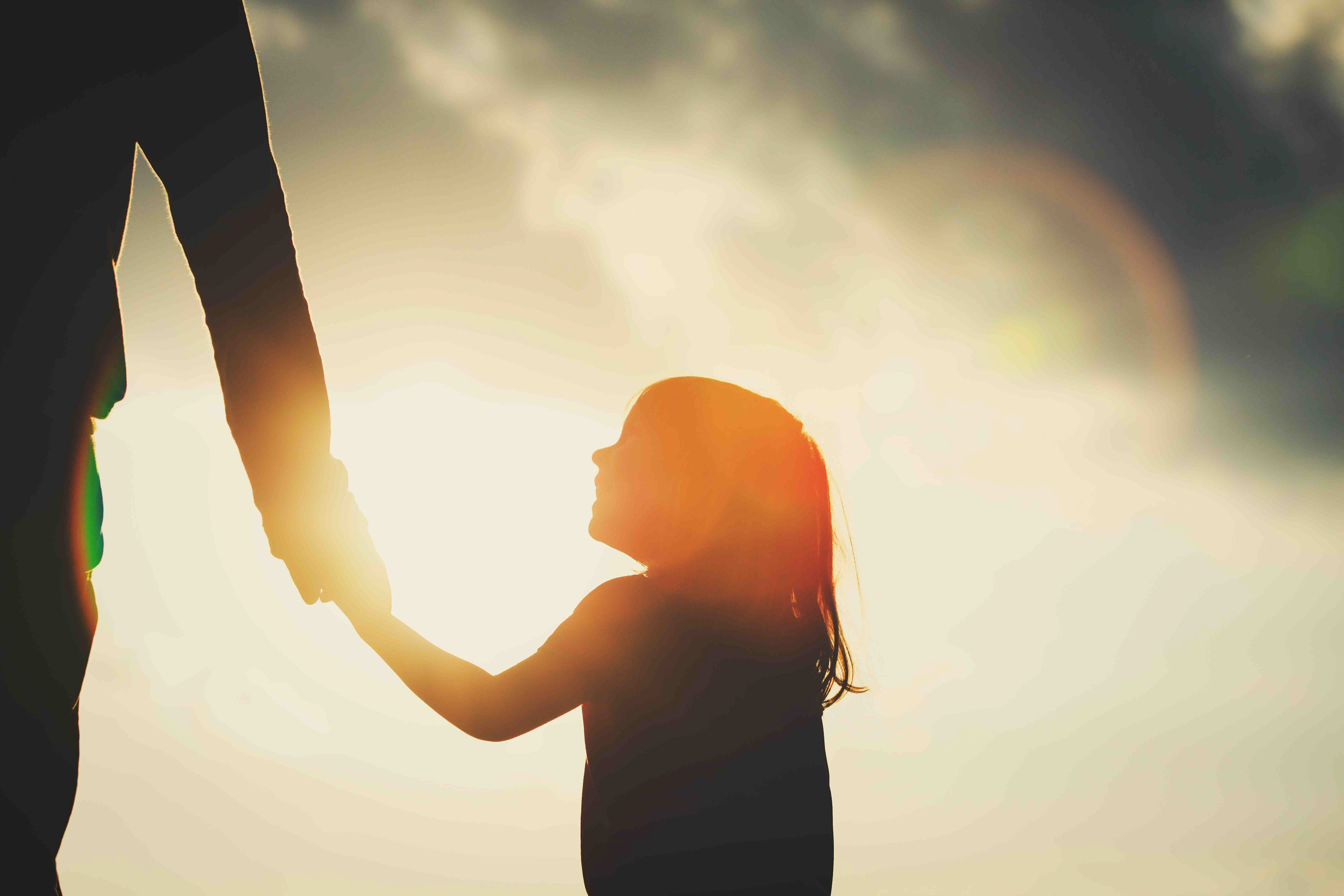 Parent tenant la main de son enfant pour l’accompagner avec confiance dans son développement.