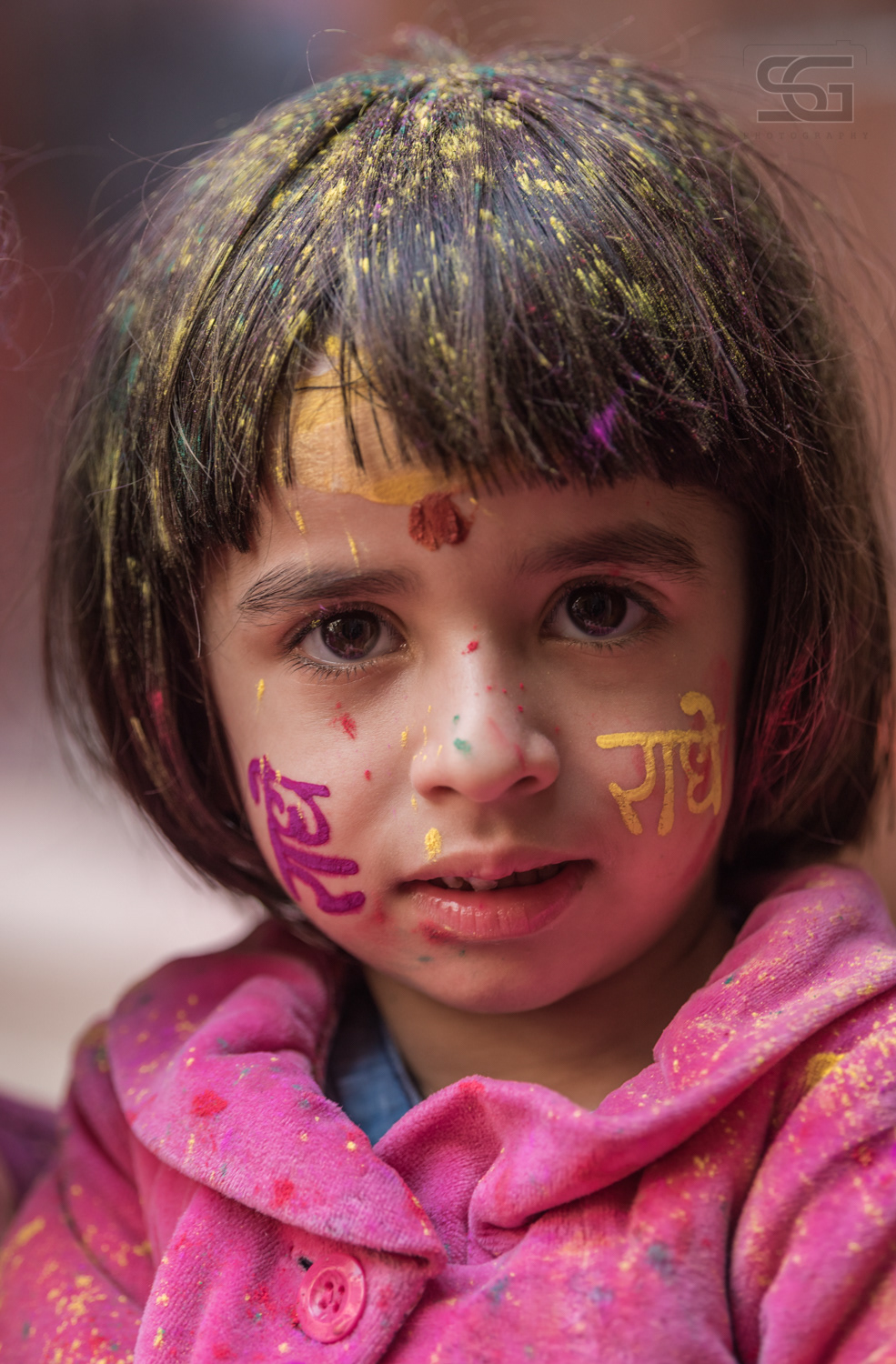 Cute little kid celebrating holi with "radhe raadhe" tattoo on the face