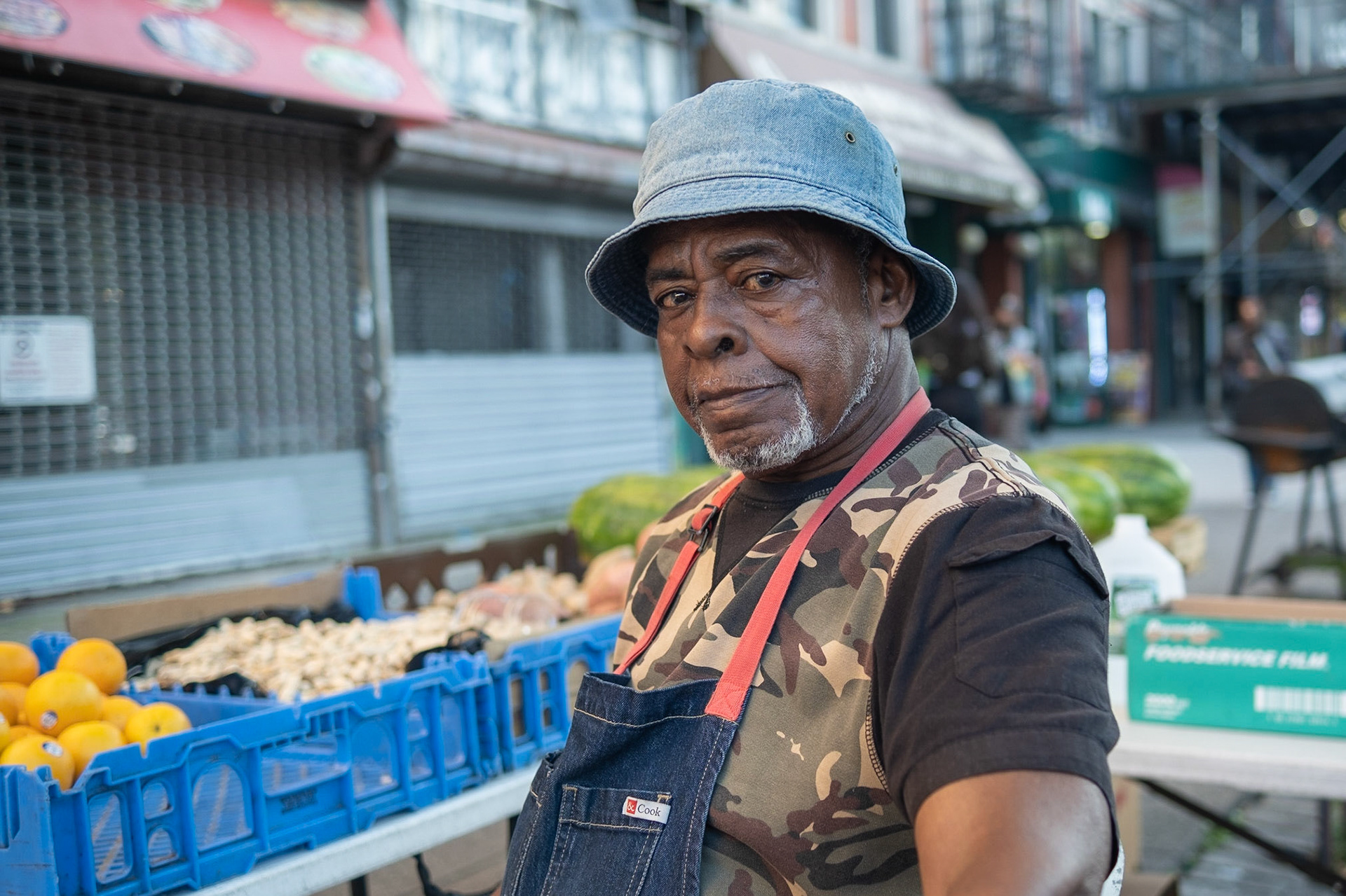 Rafph Heywood, a fruit stand owner in lower Harlem, sits at his stand surrounded by oranges, peanuts and watermelons in New York City, Sunday, Oct. 01, 2023, Photo Tabius McCoy