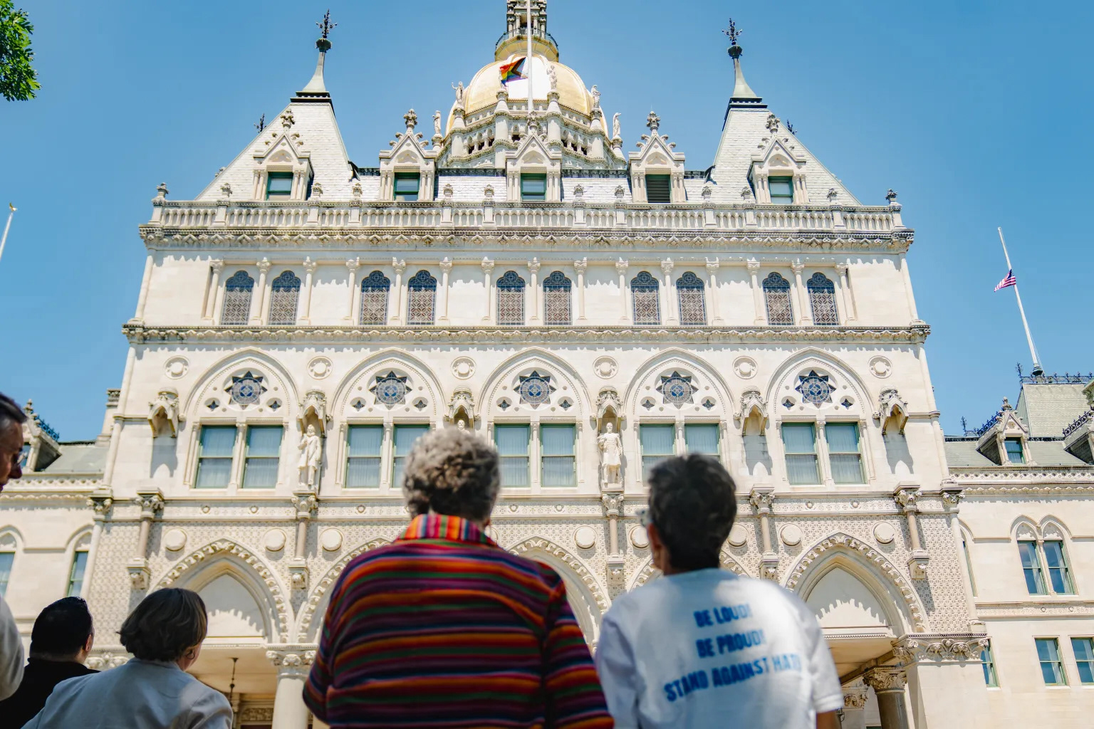 Beth Bye, commissioner of the Office of Early Childhood and a former state lawmaker, and her wife Tracey Wilson watch as the Pride flag is raised on top of the state Capitol in Hartford, Monday, June 3, 2024. They were the first same-sex couple married in Connecticut.