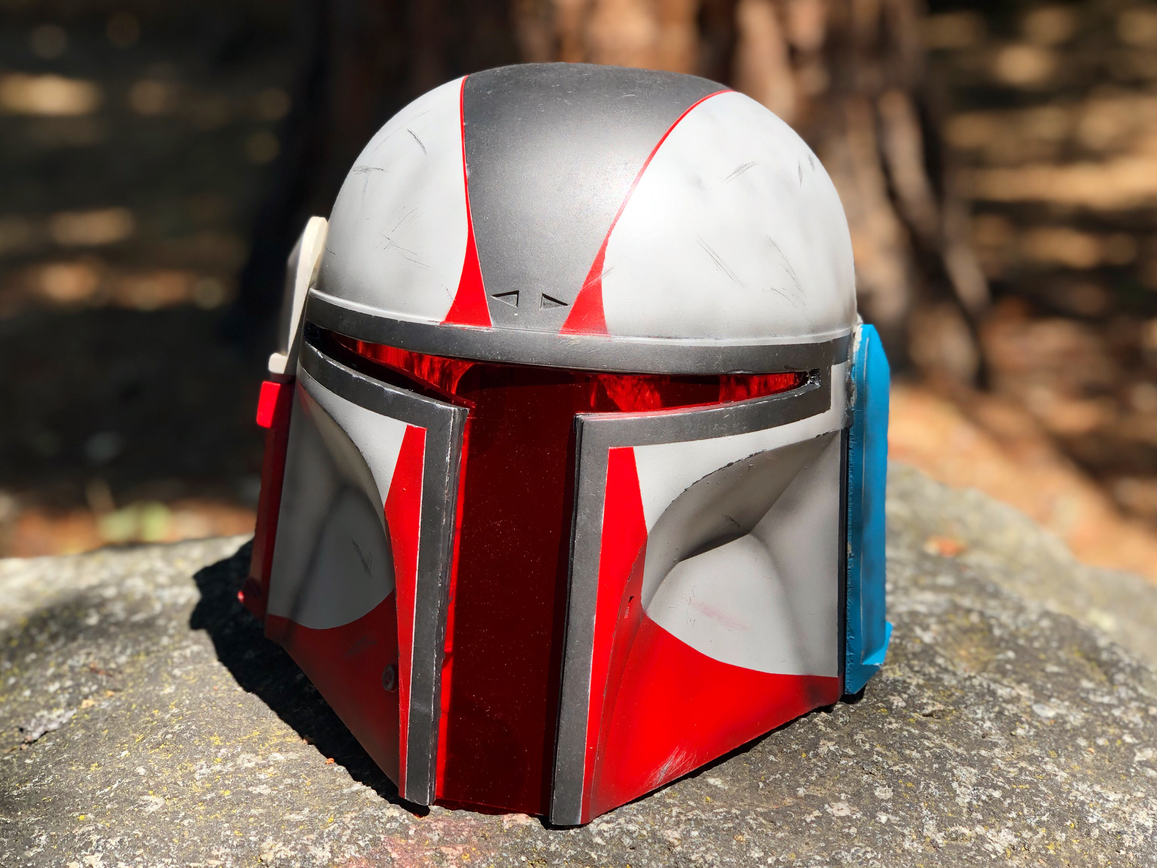 Resin cast Mandalorian helmet (red, white, and chrome). Cast from NME Props. Jun 2021.