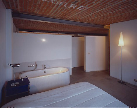 Het bad staat in de slaapkamer. De letters op het plafond verwijzen naar de vroegere functie van het gebouw.