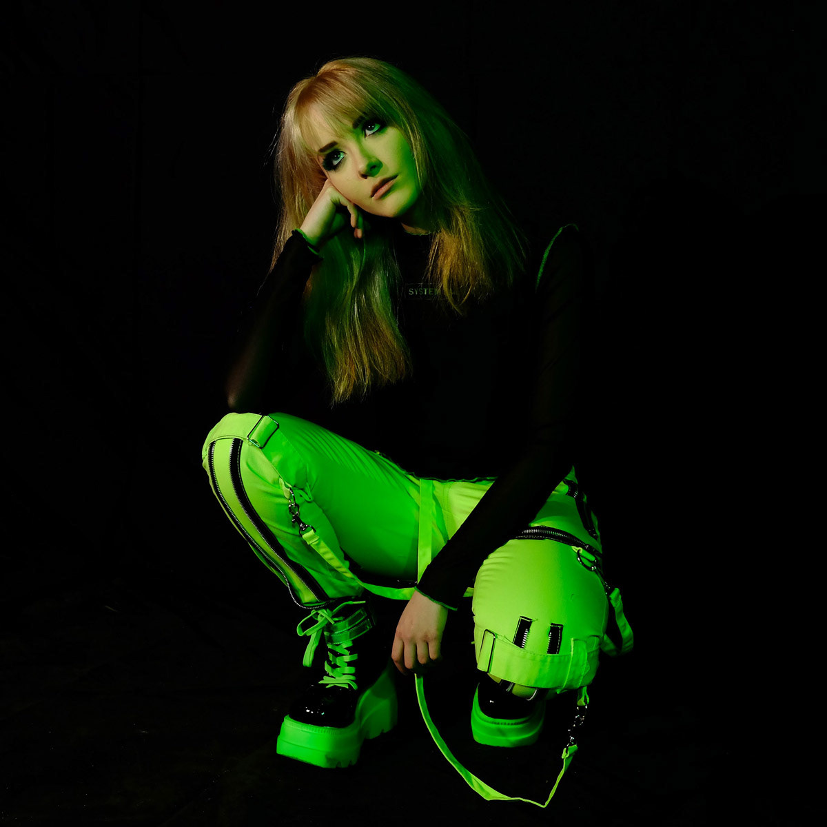 Vocalist Emma Shippen knelt down, looking upwards.