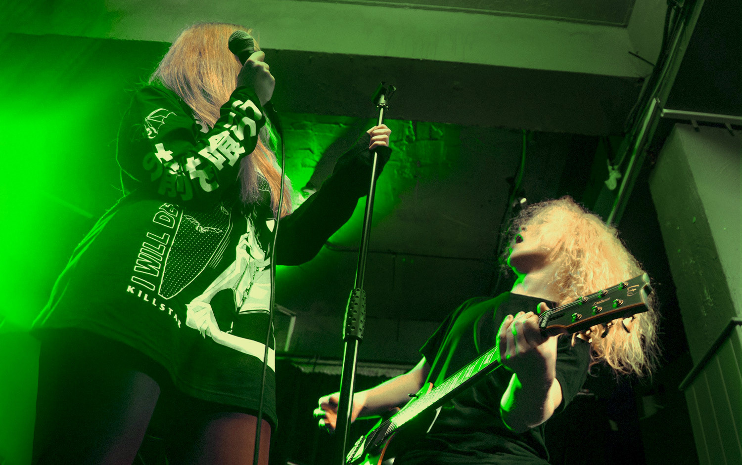 Live photo of DACARA vocalist and guitarist with green stage lighting