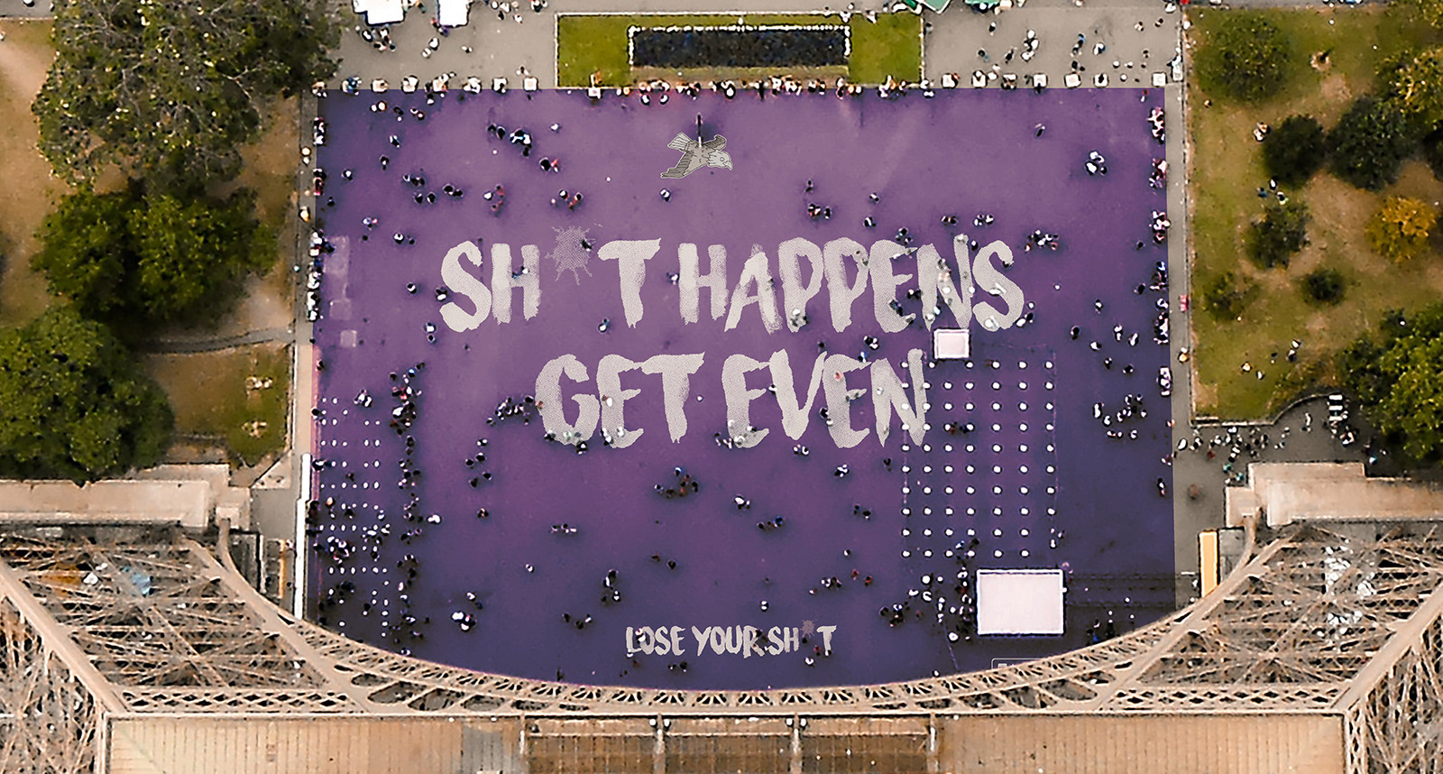Floor decal with slogan 'Shit happens, get even' installed at the bottom of the Eiffel Tower
