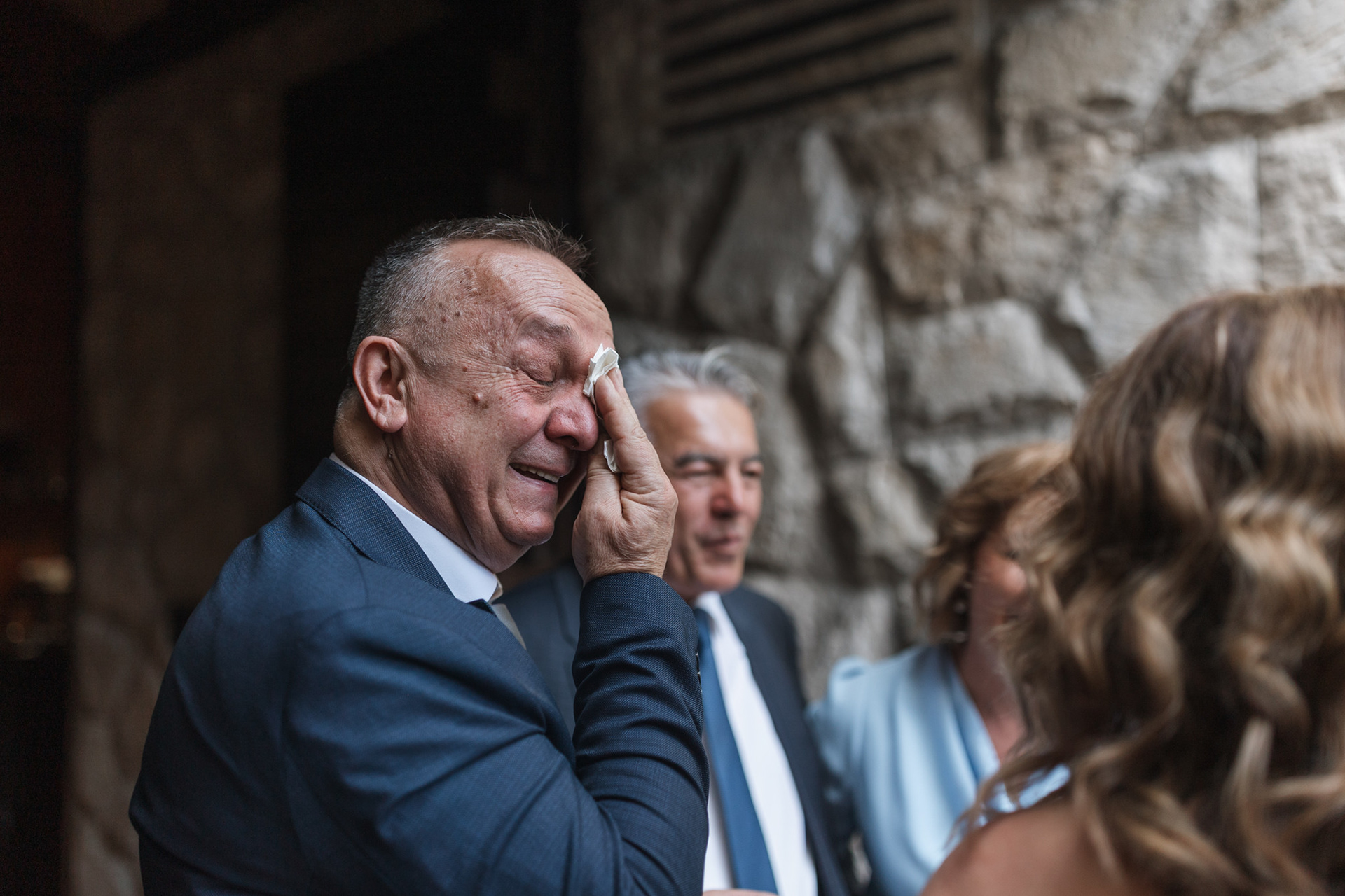 Father wiping away a tear during his daughter's wedding ceremony in church
