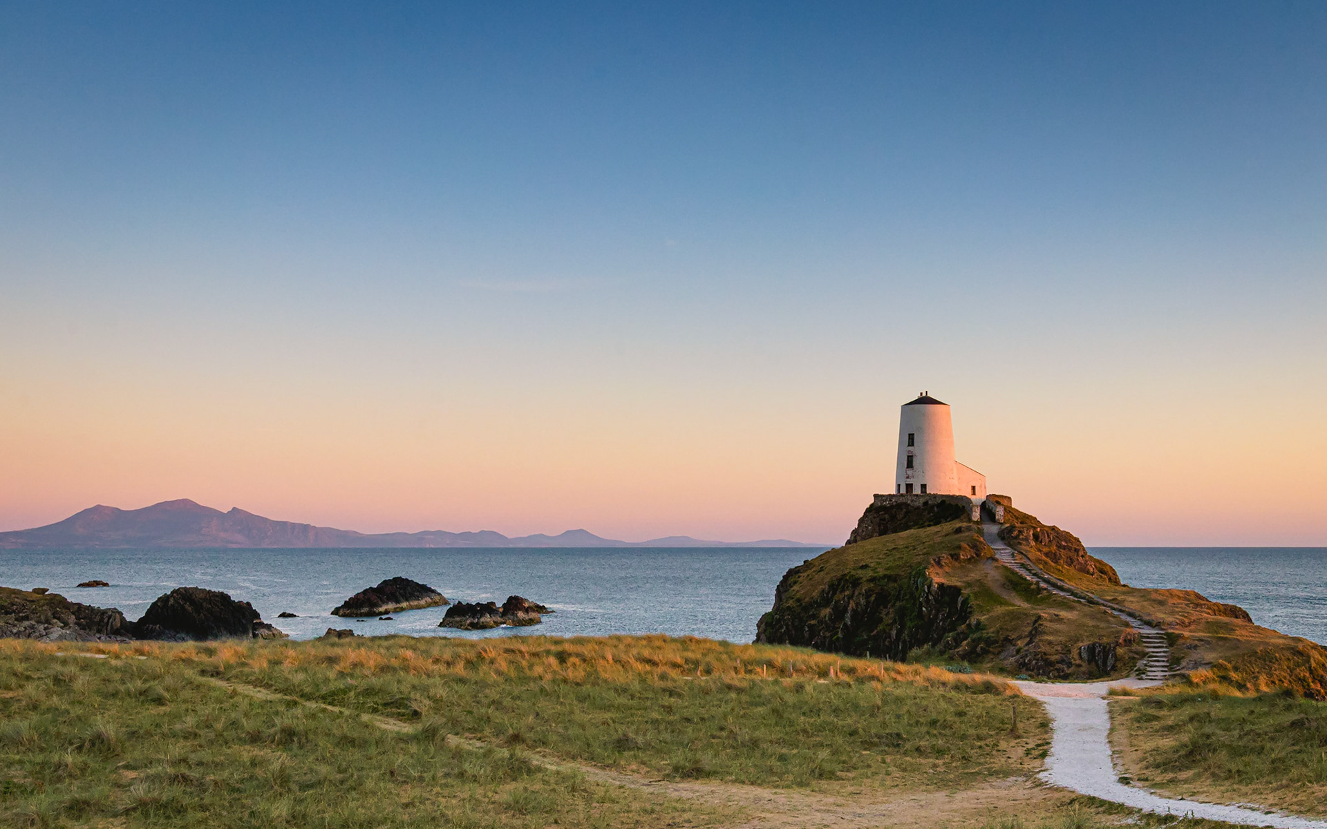 Evening view of Tŵr Bach lighthouse at Ynys Llanddwyn with the sun setting.