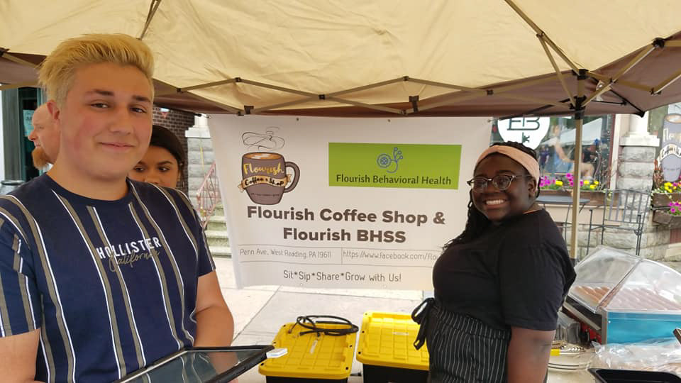 Employees In Front of Banner with Logo