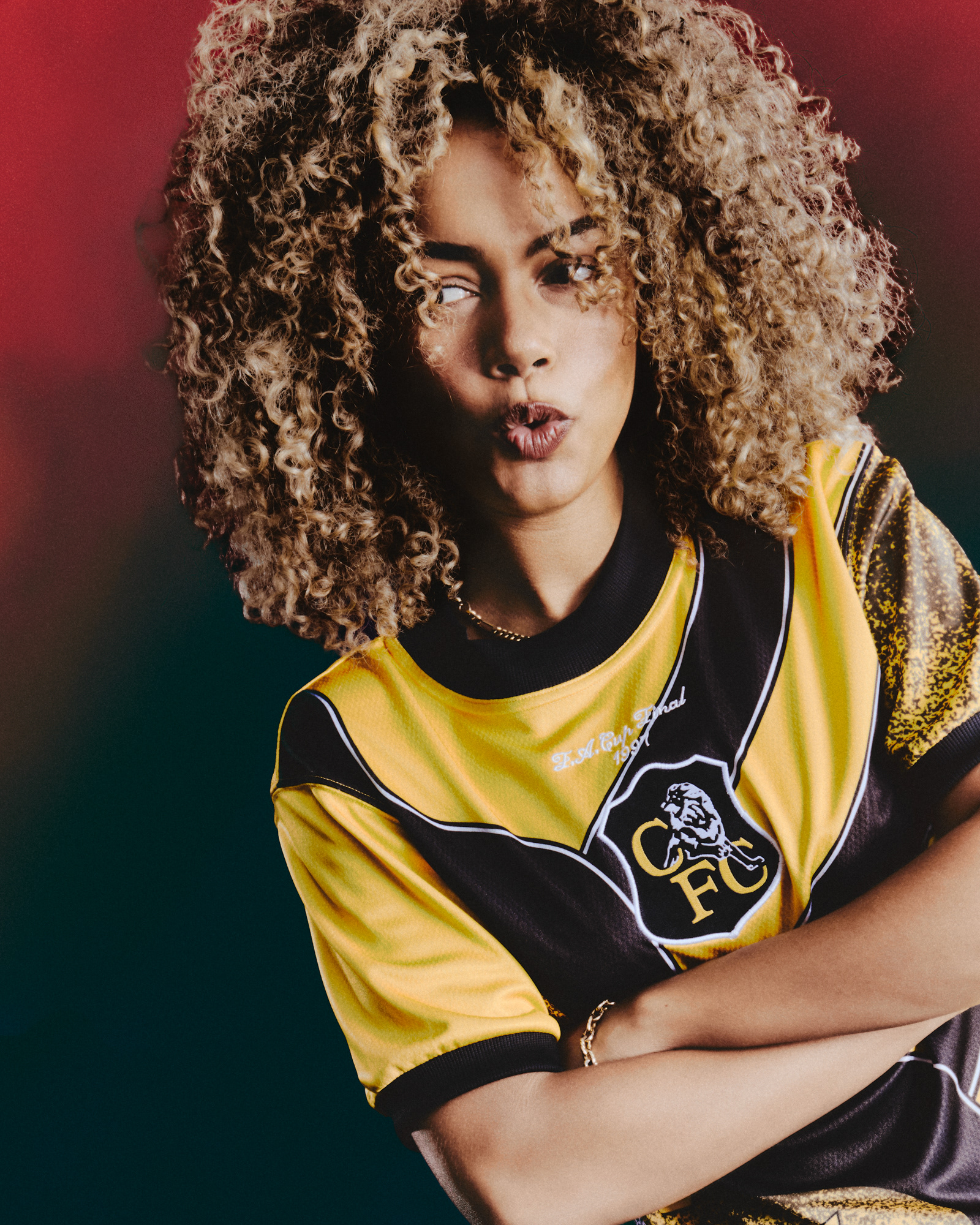 a Chelsea football player wearing their vintage collection "Play loud", very bright yellow football (soccer) jersey inspired by the 90s goal keeper kits from the club.