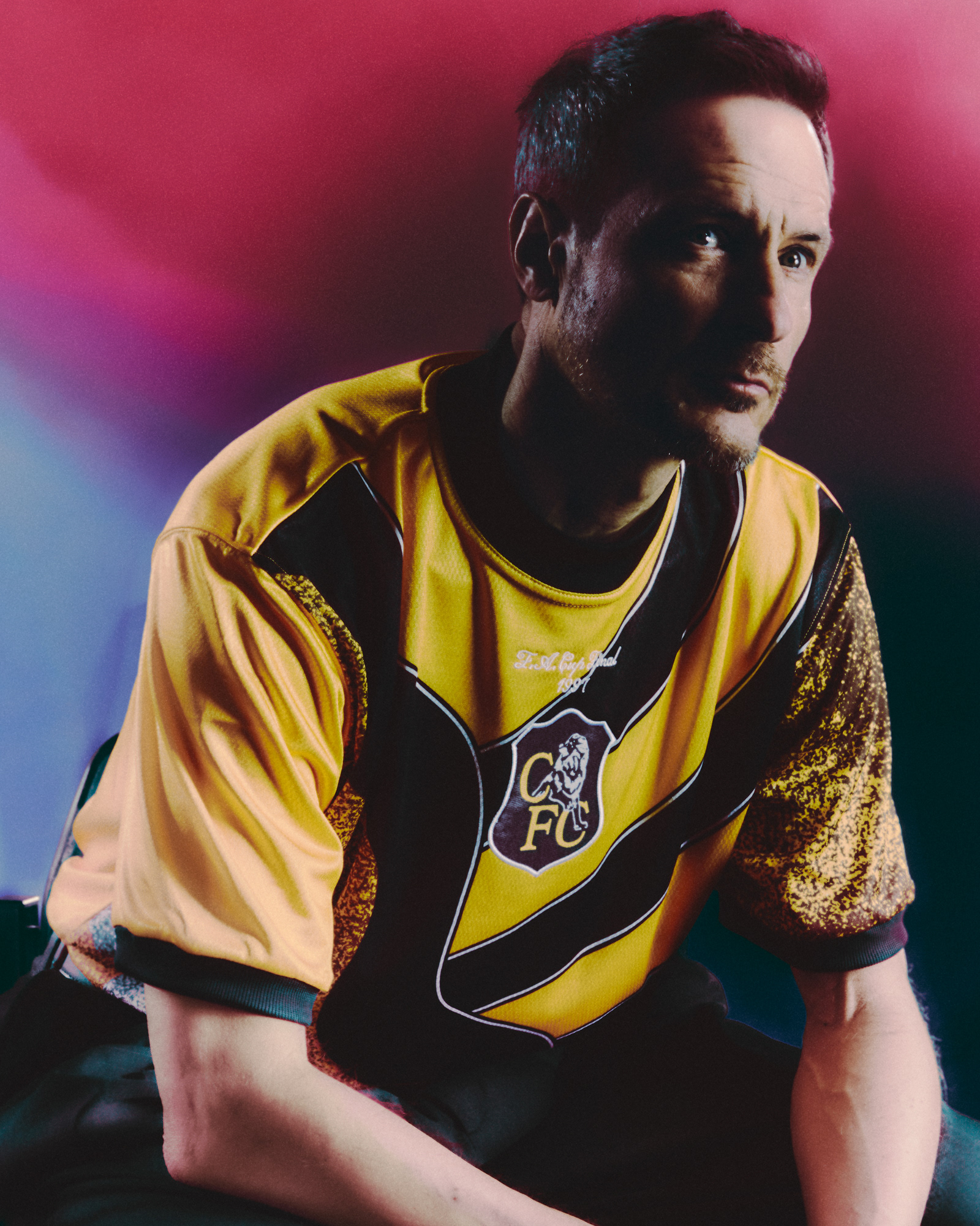 a Chelsea football player wearing their vintage collection "Play loud", very bright yellow football (soccer) jersey inspired by the 90s goal keeper kits from the club.