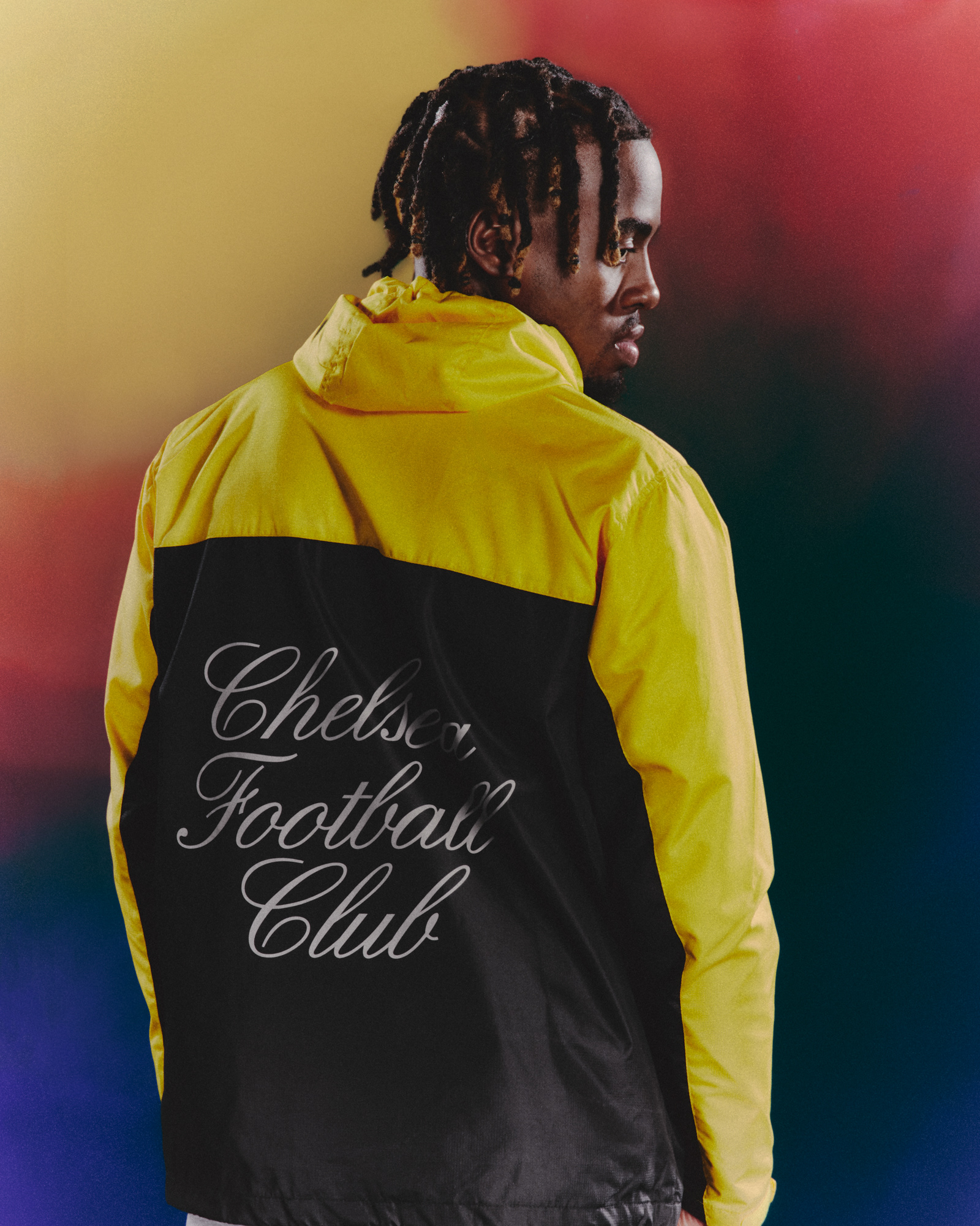 a Chelsea football player wearing their vintage collection "Play loud", very bright yellow and black parka inspired by the 90s goal keeper kits from the club.