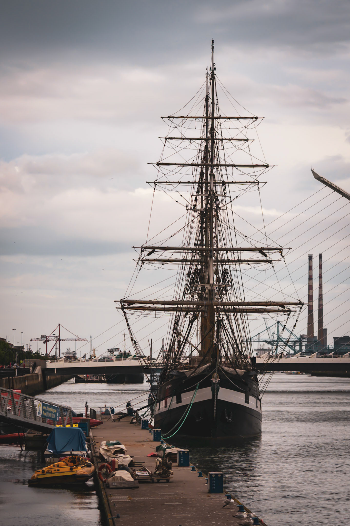 A visual look at Dublin’s maritime history, where the wooden masts and rigging of a famine ship replica stand against the modern city skyline.