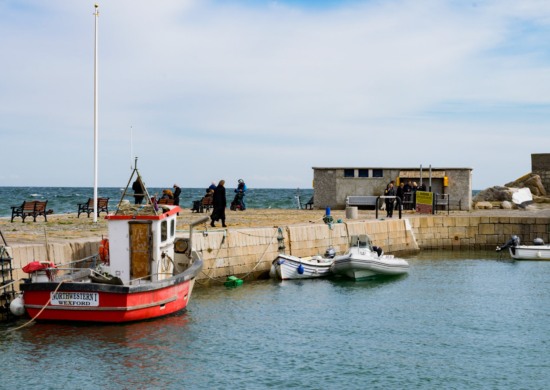Sunlit waters and shifting tides along the historic stone walls of Bullock Harbour, framed by the open expanse of Dublin Bay.