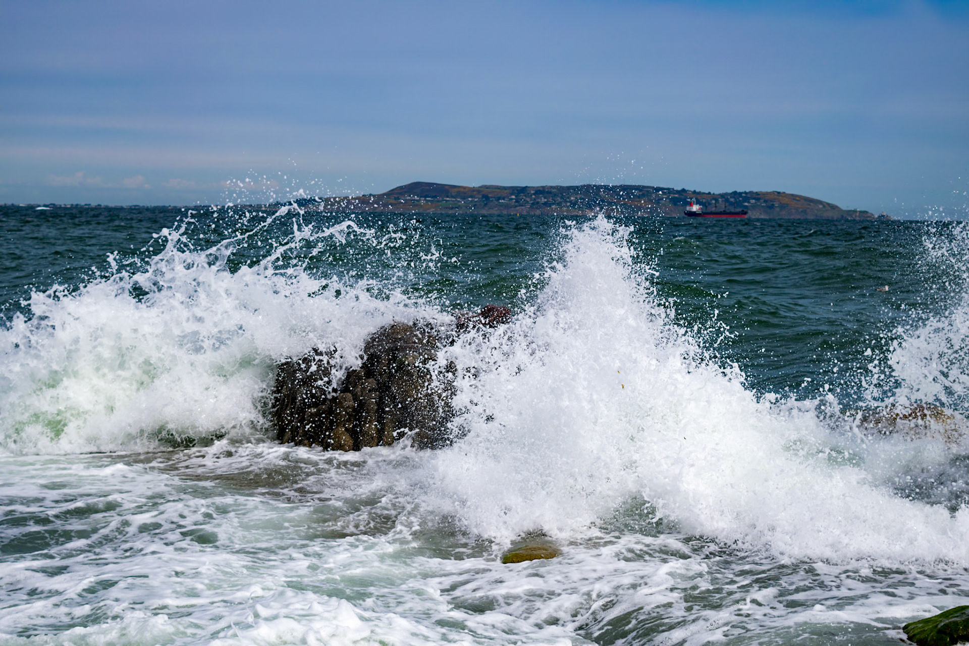 Sunlit waters and shifting tides along the historic stone walls of Bullock Harbour, framed by the open expanse of Dublin Bay.