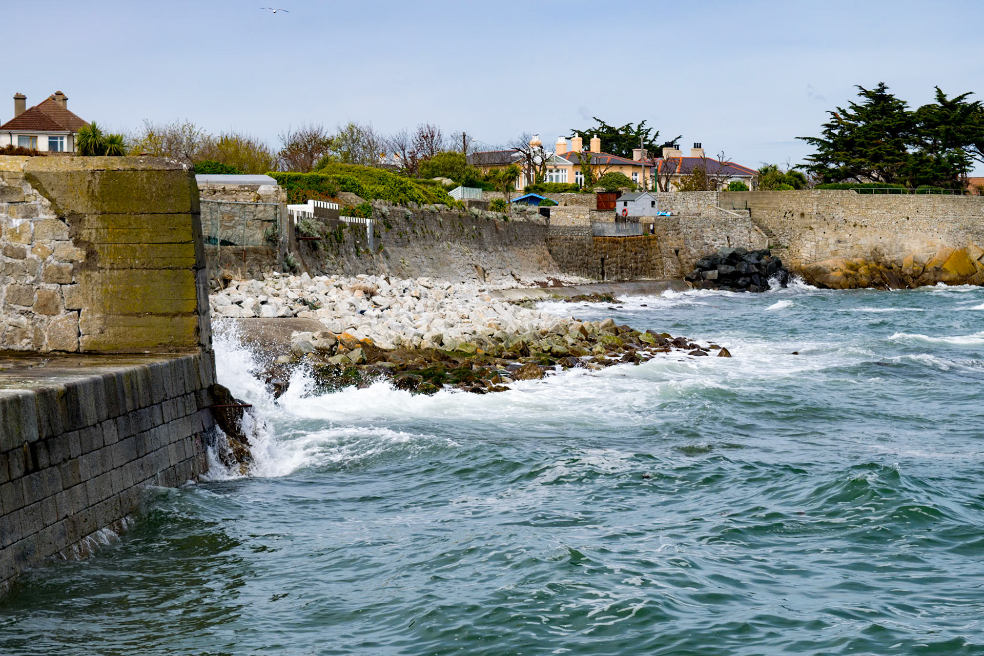 Sunlit waters and shifting tides along the historic stone walls of Bullock Harbour, framed by the open expanse of Dublin Bay.