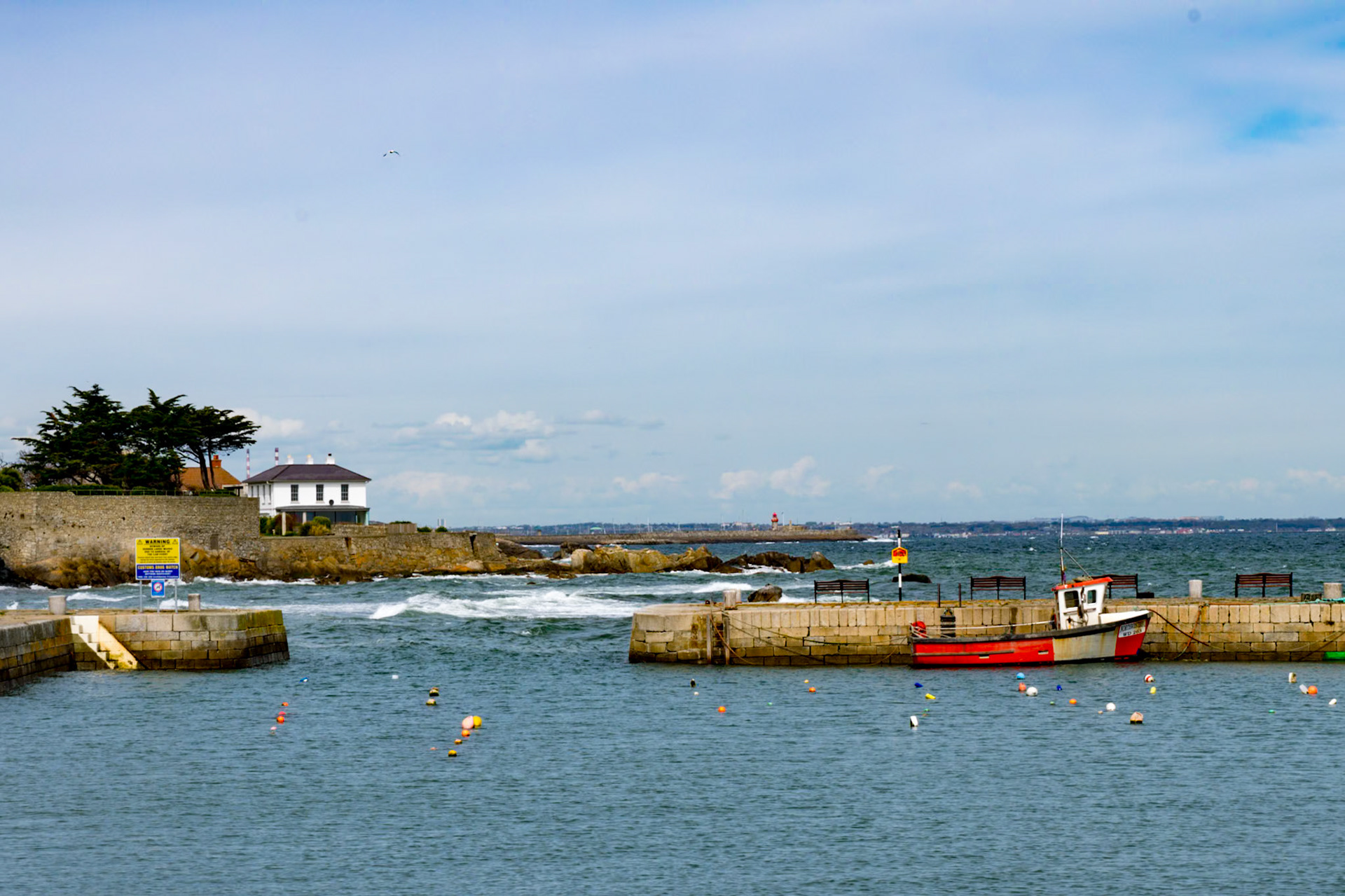 Sunlit waters and shifting tides along the historic stone walls of Bullock Harbour, framed by the open expanse of Dublin Bay.