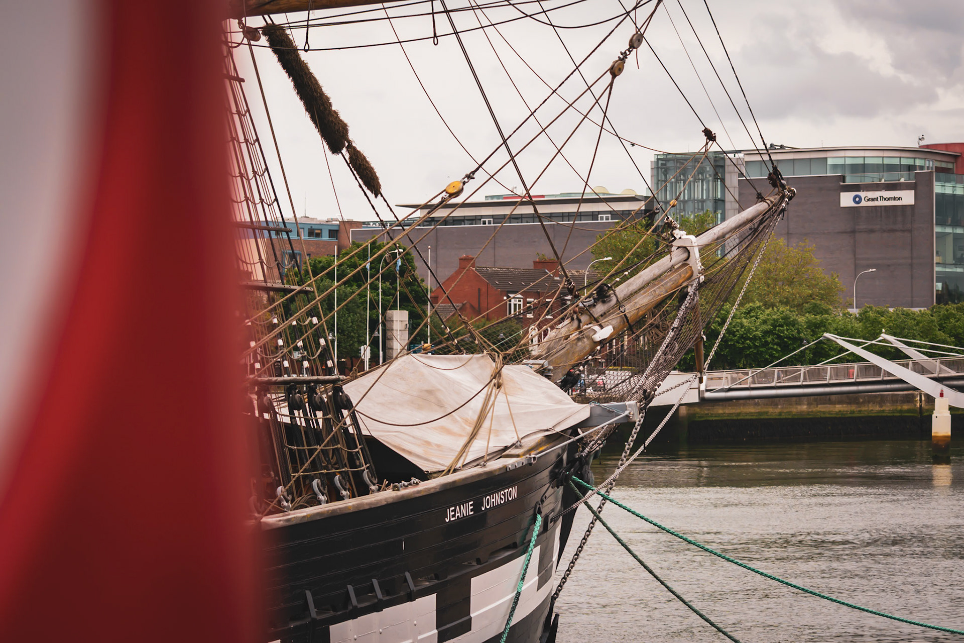 A visual look at Dublin’s maritime history, where the wooden masts and rigging of a famine ship replica stand against the modern city skyline.