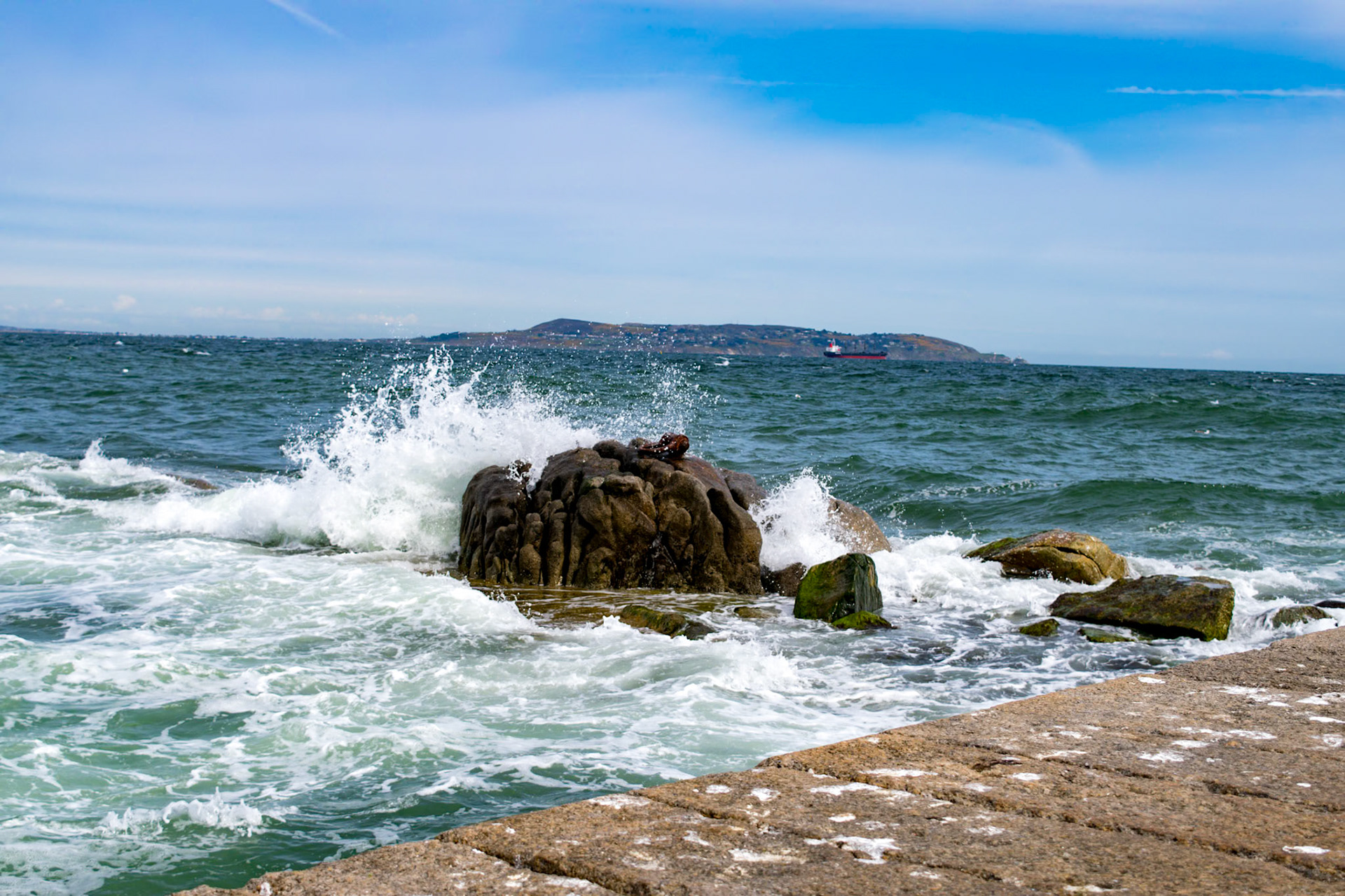 Sunlit waters and shifting tides along the historic stone walls of Bullock Harbour, framed by the open expanse of Dublin Bay.
