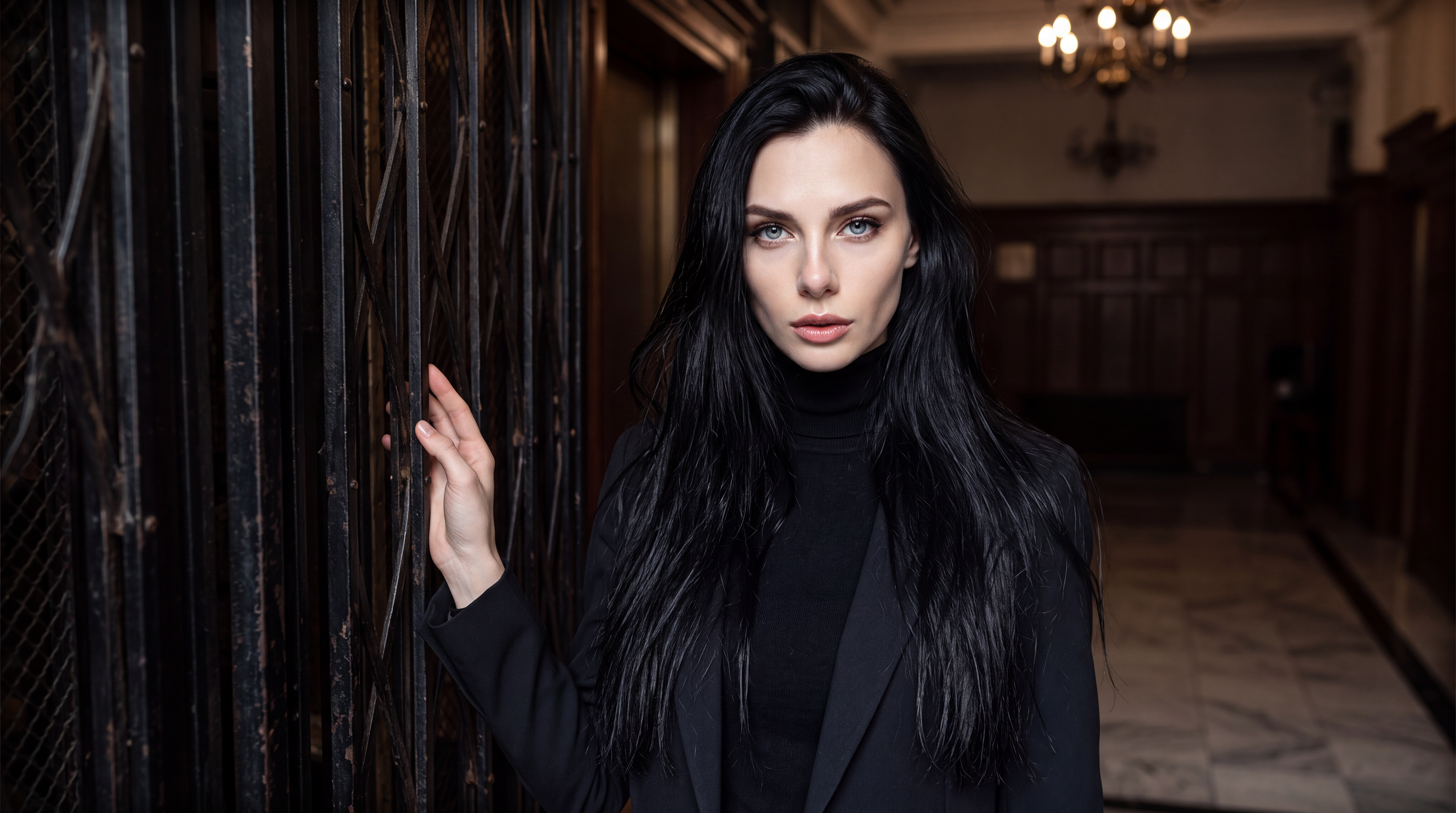 Cinematic editorial photograph of Demitra Kalnina in hotel hallway standing beside old elevator grate.