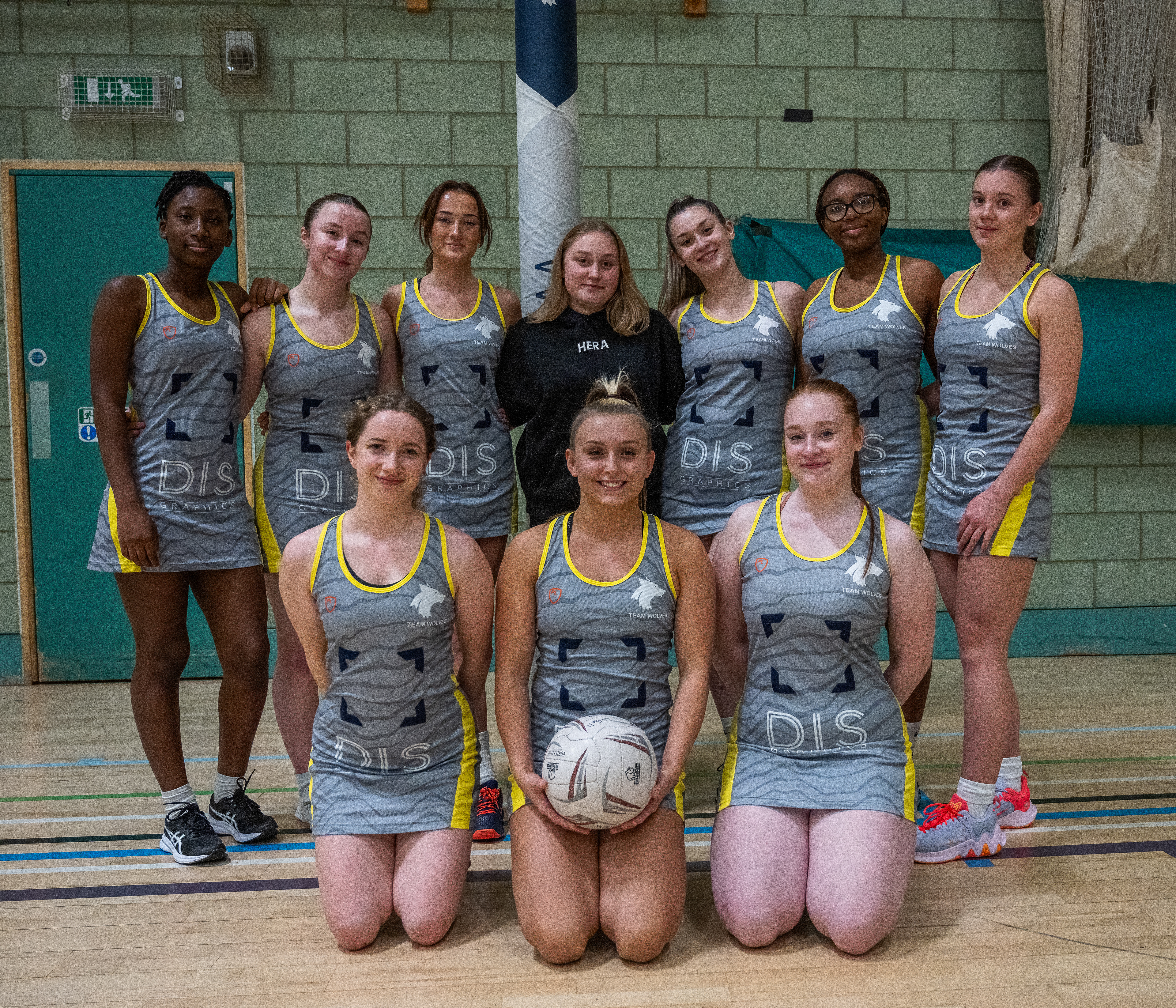 A group of young women wearing sports attire and holding a netball