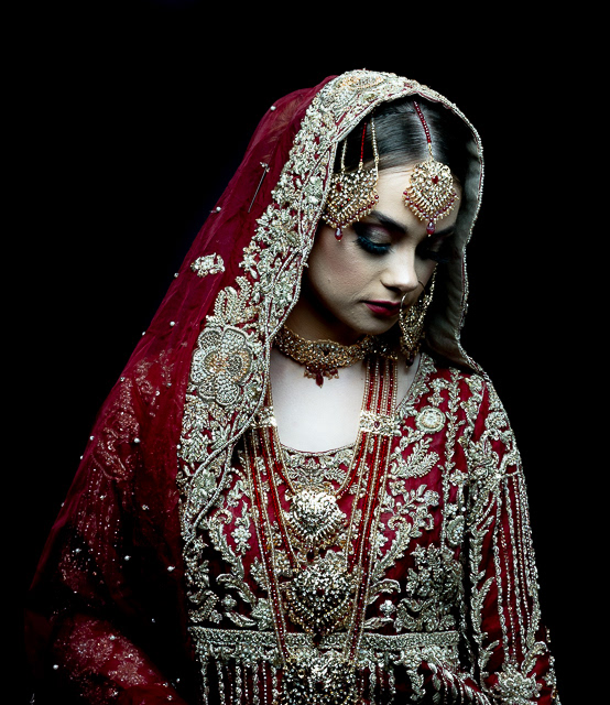 Portfolio shoot - for make-artist  A young girl dressed in traditional Asian wedding attire looks down  