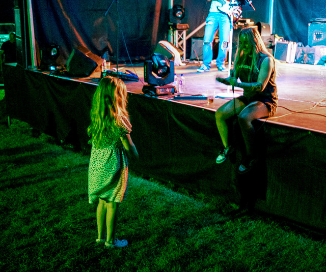 Black Country Boat Festival - Promo - A female singer sits on the edge of a stage singing to a little girl who is stood at the front of the stage watching her