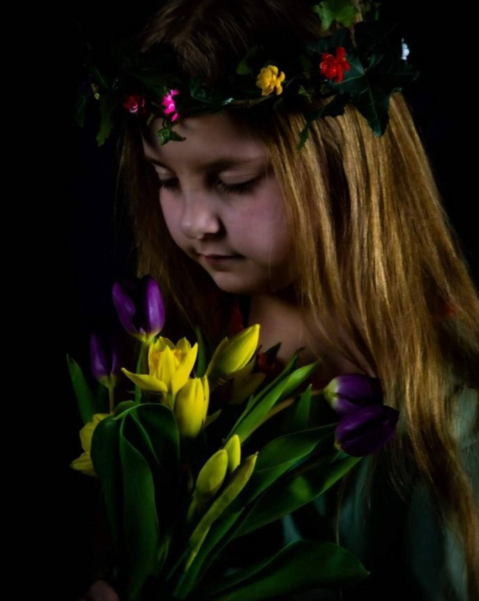 Easter Shoot A young girl wearing a garland of flowers in her hair, she is looking down at a bunch of flowers that she holds