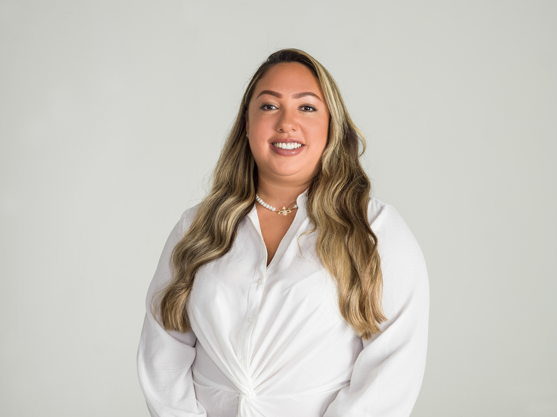 Proser Magazine Shoot A woman with long hair wearing a white blouse smiles and looks at the camera 