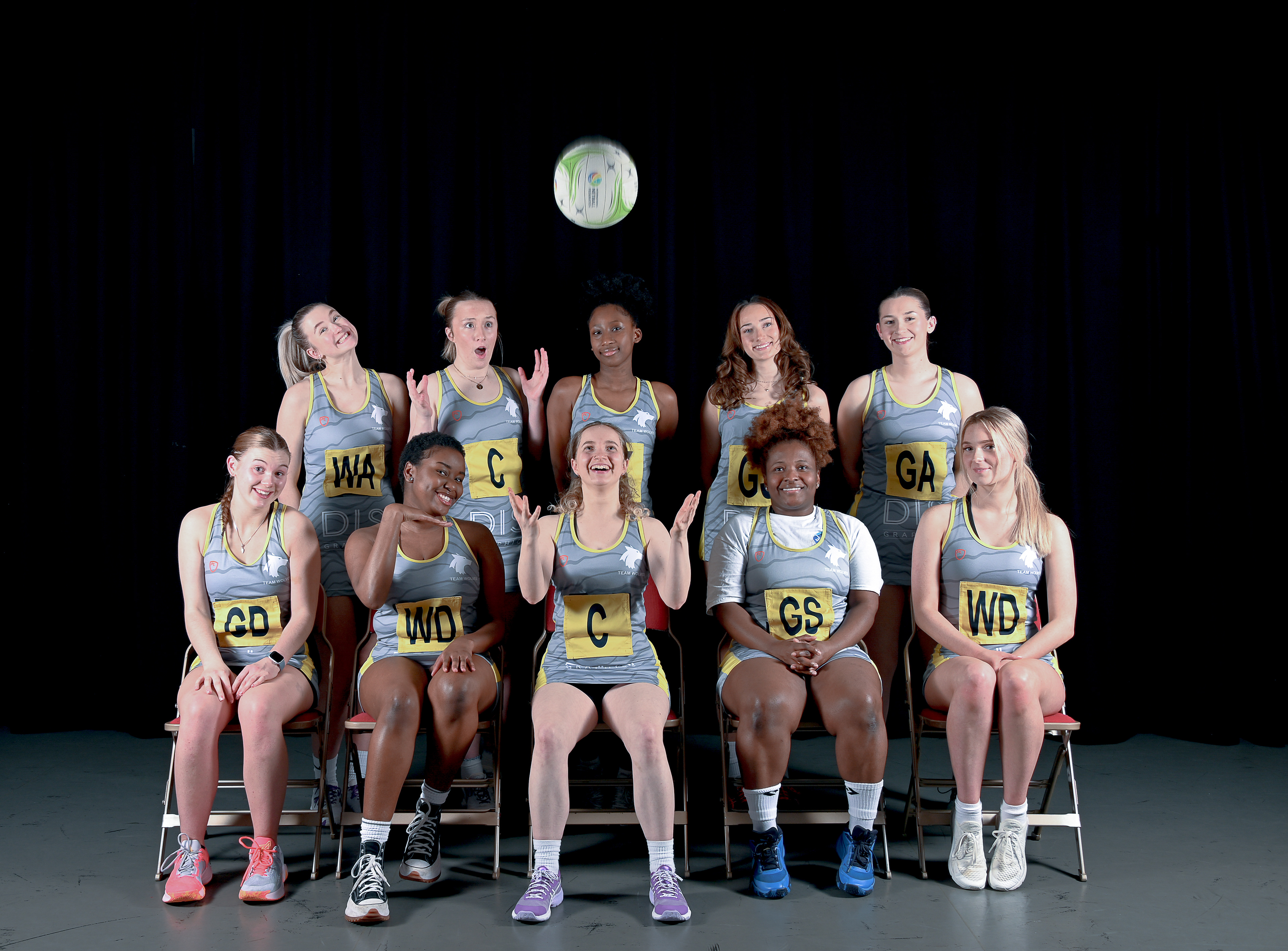 A group of women in sports attire one of them throws a ball in the air
