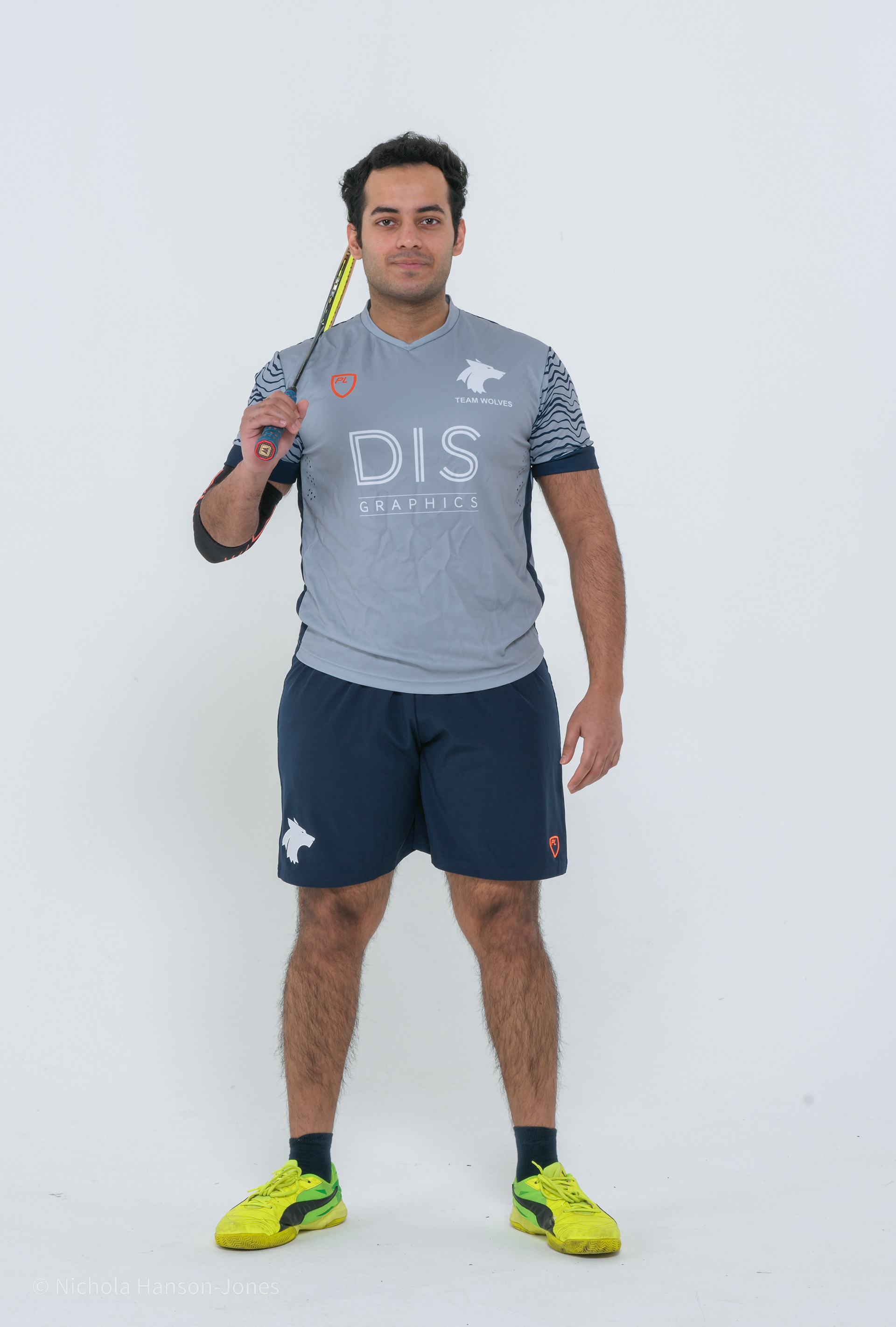 A young man in sports attire holding a badminton racket