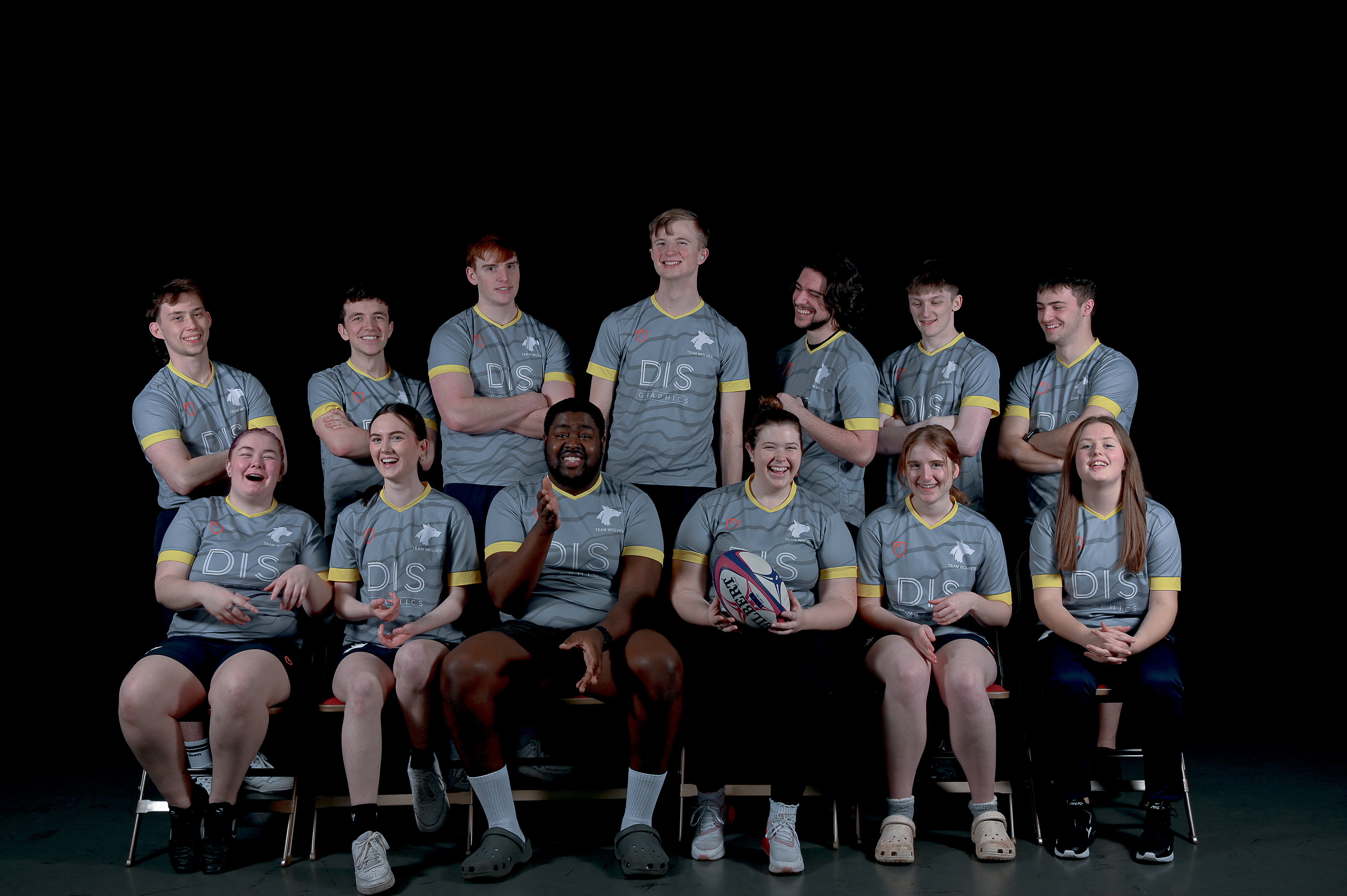 A team of young men and women dressed in sports wear, one of them hold a rugby ball