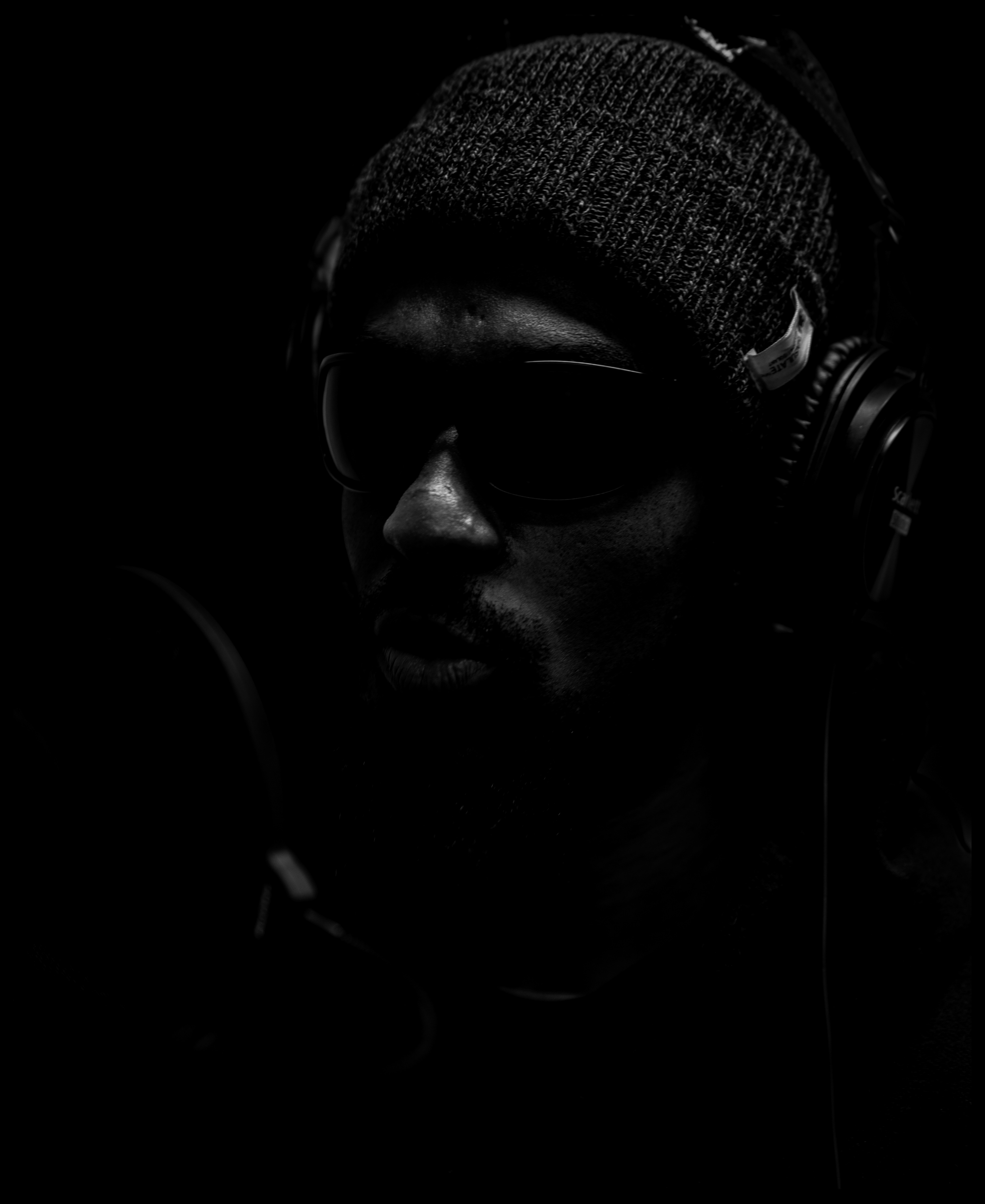 Women in Photography Exhibition 2024 A black man wearing a hat and head phones , he also wears dark glasses , he faces slightly off to the right